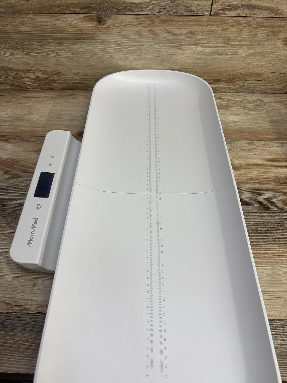 Digital baby scale with measuring ruler on a wood surface, ideal for infant weight tracking