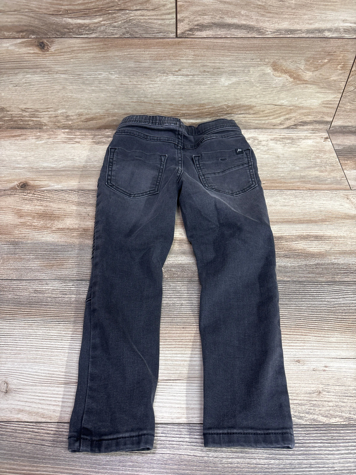 Back view of Art Class drawstring moto jeans in black, size 4T, showing back pockets on a wood-look background