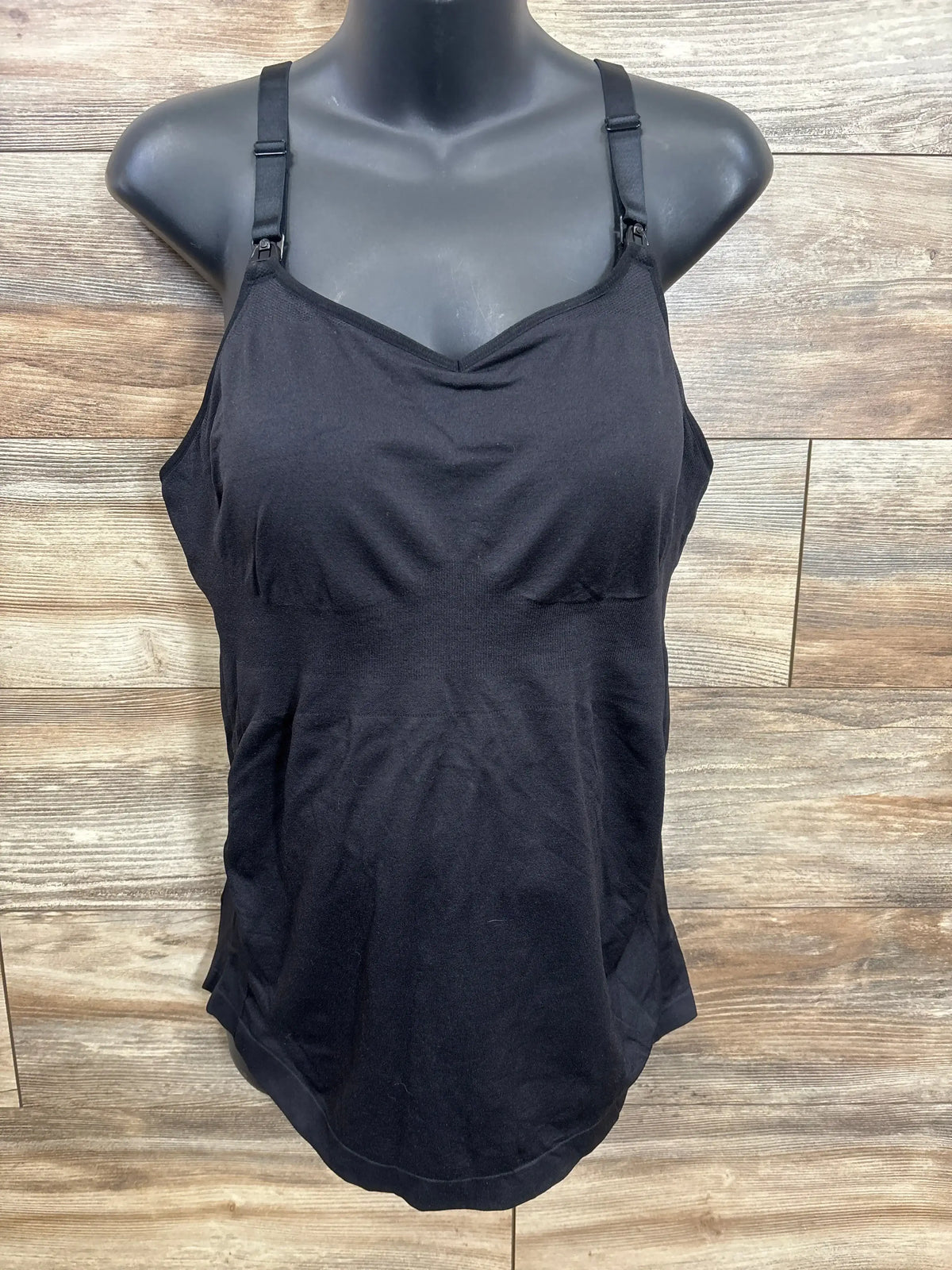 Black maternity nursing tank top with adjustable straps on mannequin, wood background