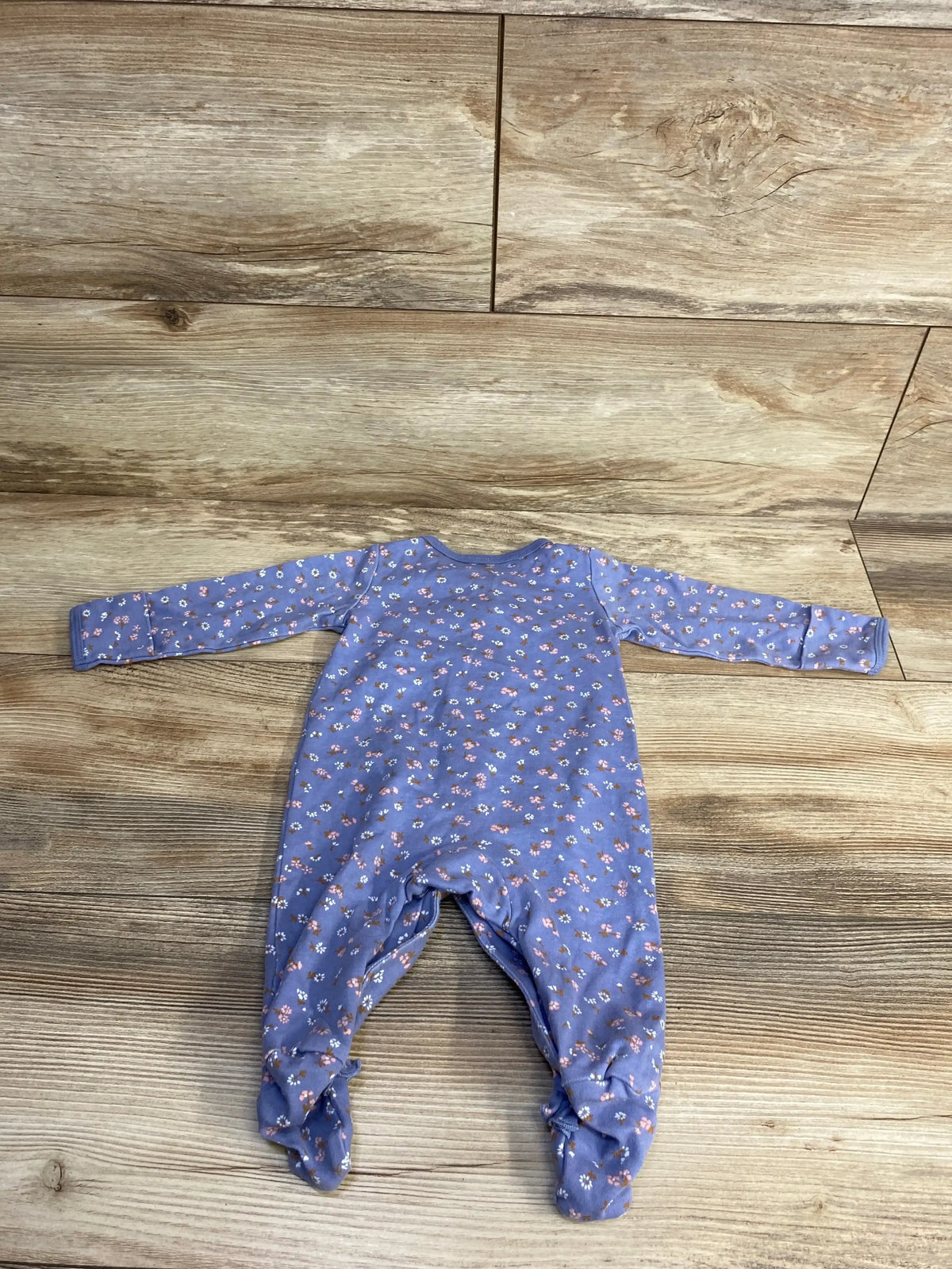 Purple floral baby sleeper laid flat on wooden floor