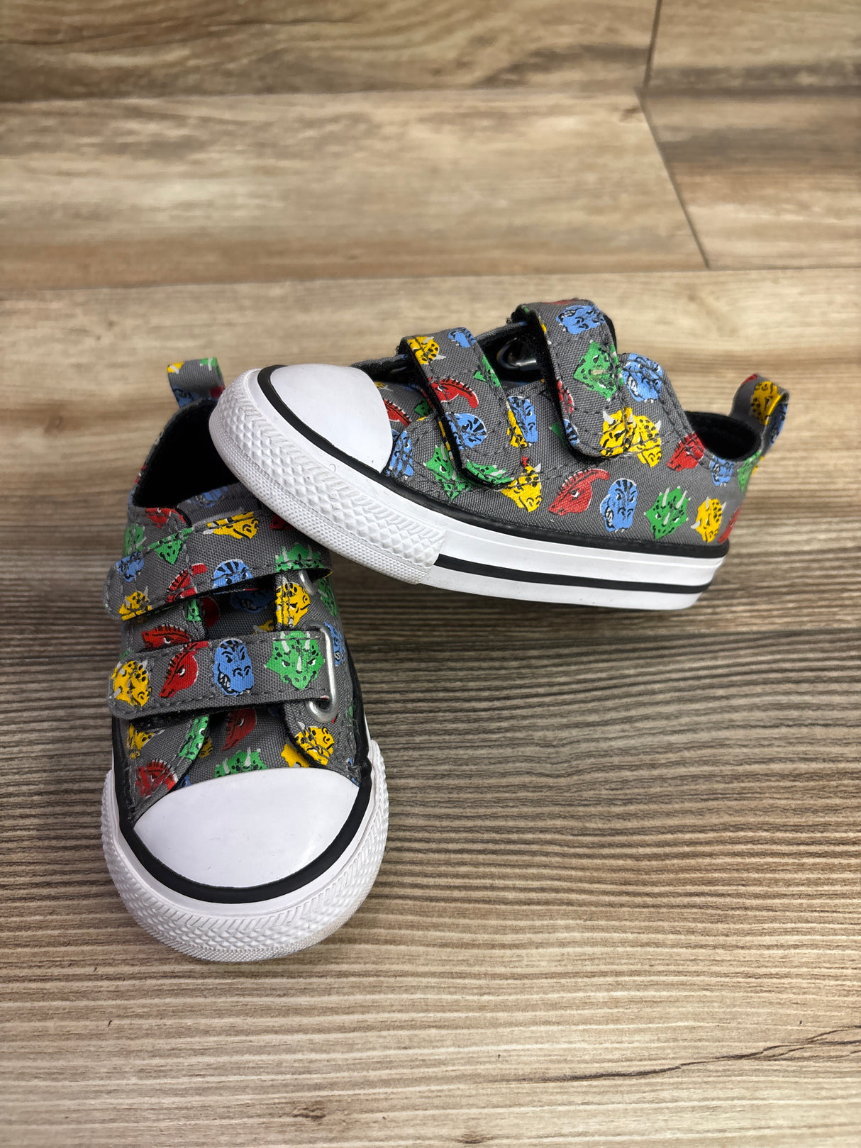 Angled view of gray Converse Chuck Taylor All Star 2V Dino sneakers with colorful prints on wood flooring