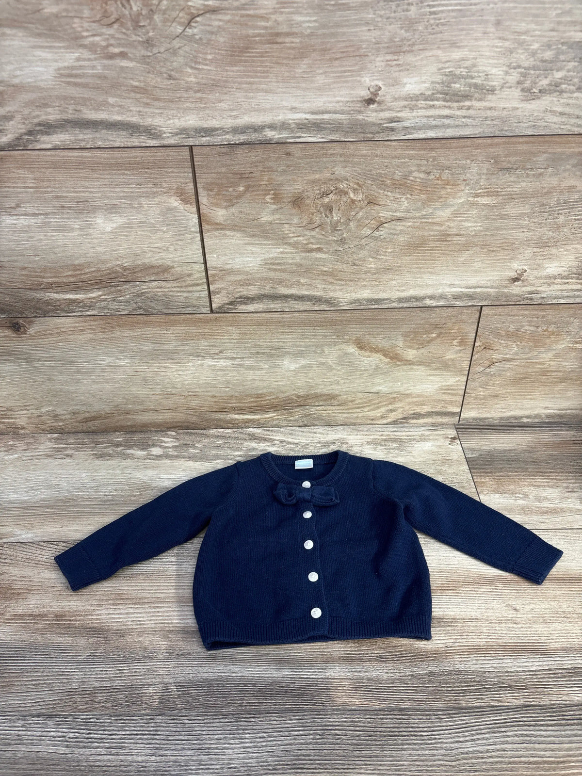 Front view of Edgehill Collection navy knit cardigan showcasing bow detail and button front on a wood floor