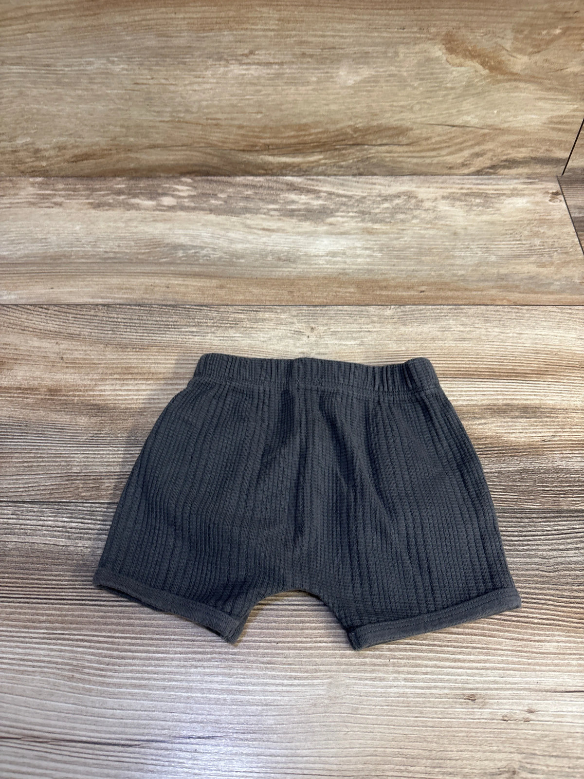 Flat lay of Modern Moments drawstring shorts showing ribbed knit texture and elastic waistband on wood background