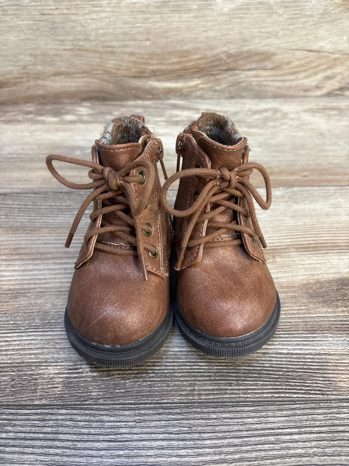 Brown lace-up toddler boots with faux fur lining on wood background