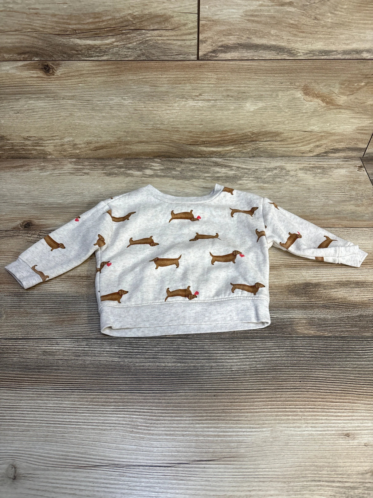 Gray baby sweatshirt with dachshund dog print, long sleeves, laid on wooden floor