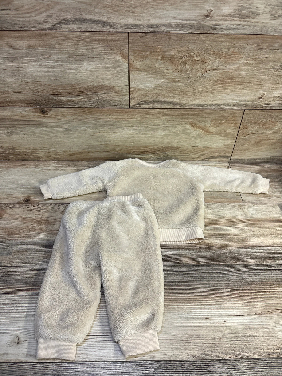 Flat lay of Pekkle 2-piece beige plush sweatshirt and pants set showcasing soft fuzzy texture and ribbed cuffs on a wood plank background