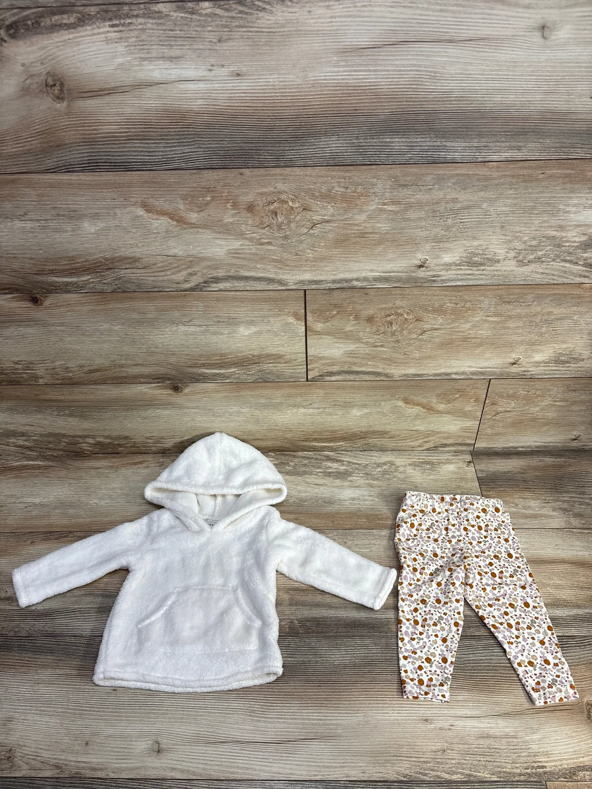 Baby white hooded fleece sweatshirt with floral patterned leggings on wooden floor