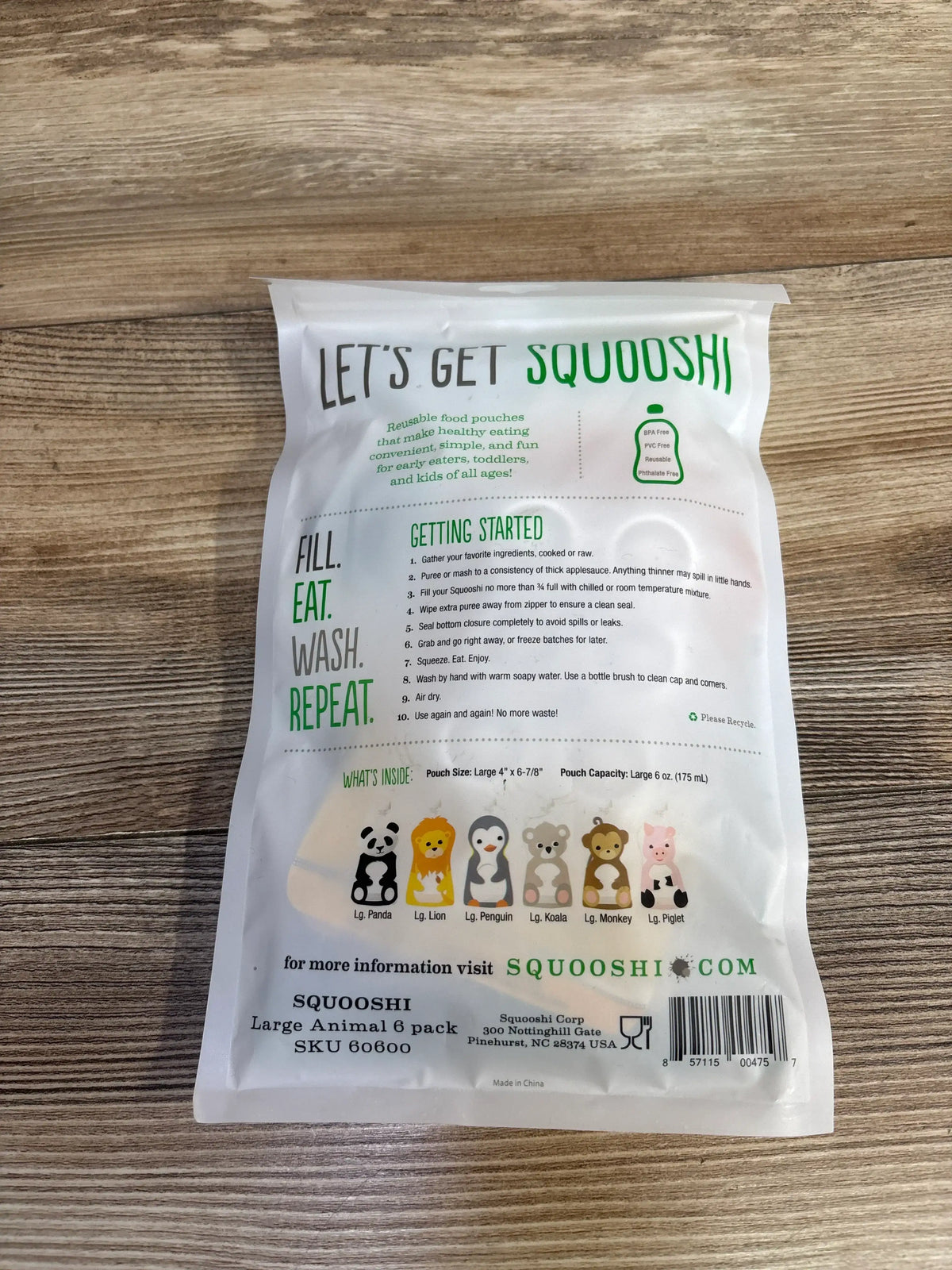 Squooshi reusable food pouch packaging on wood, featuring animal designs and usage instructions.