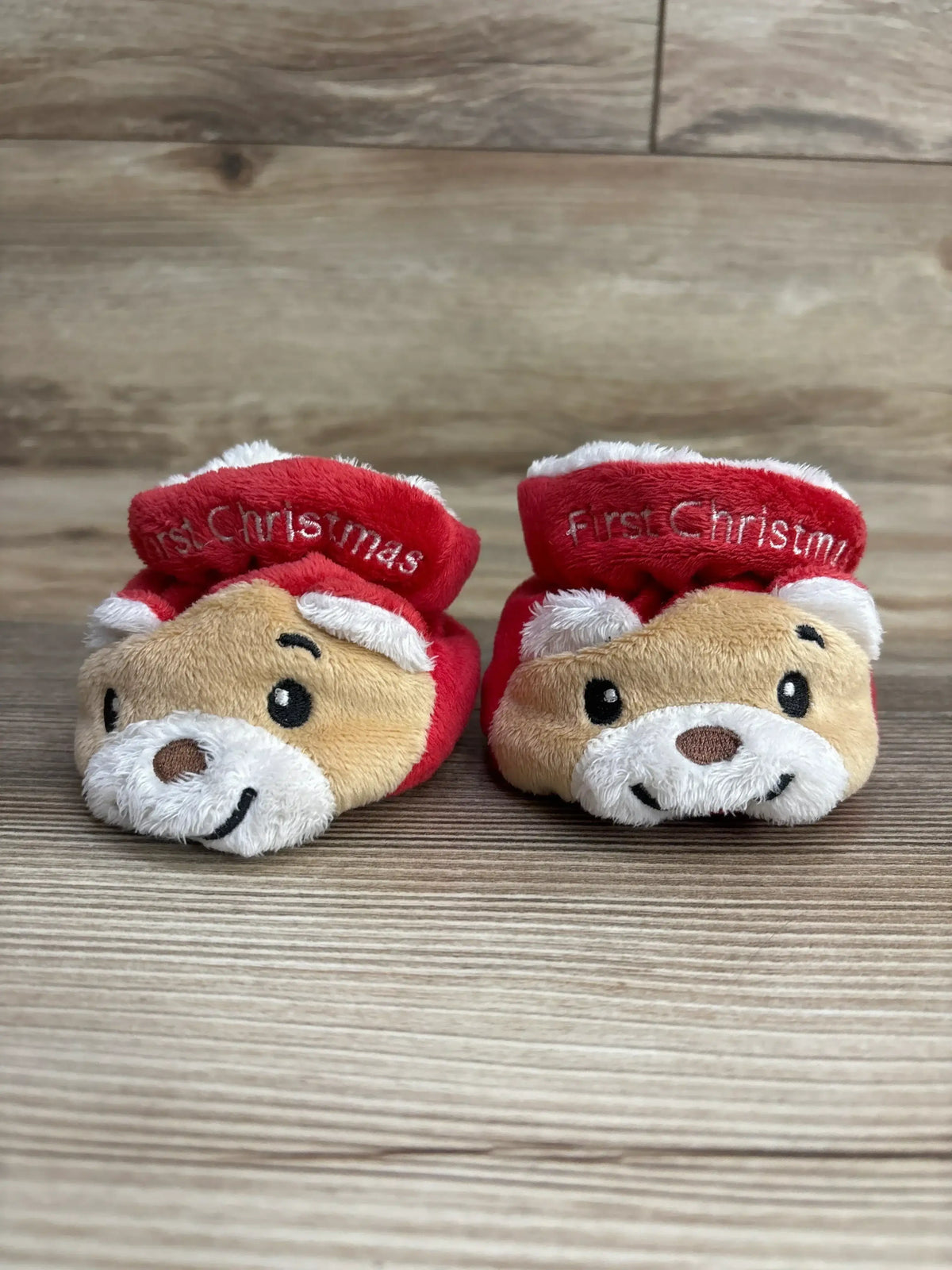 Adorable baby booties with 'First Christmas' text, featuring cute reindeer faces and festive red design.