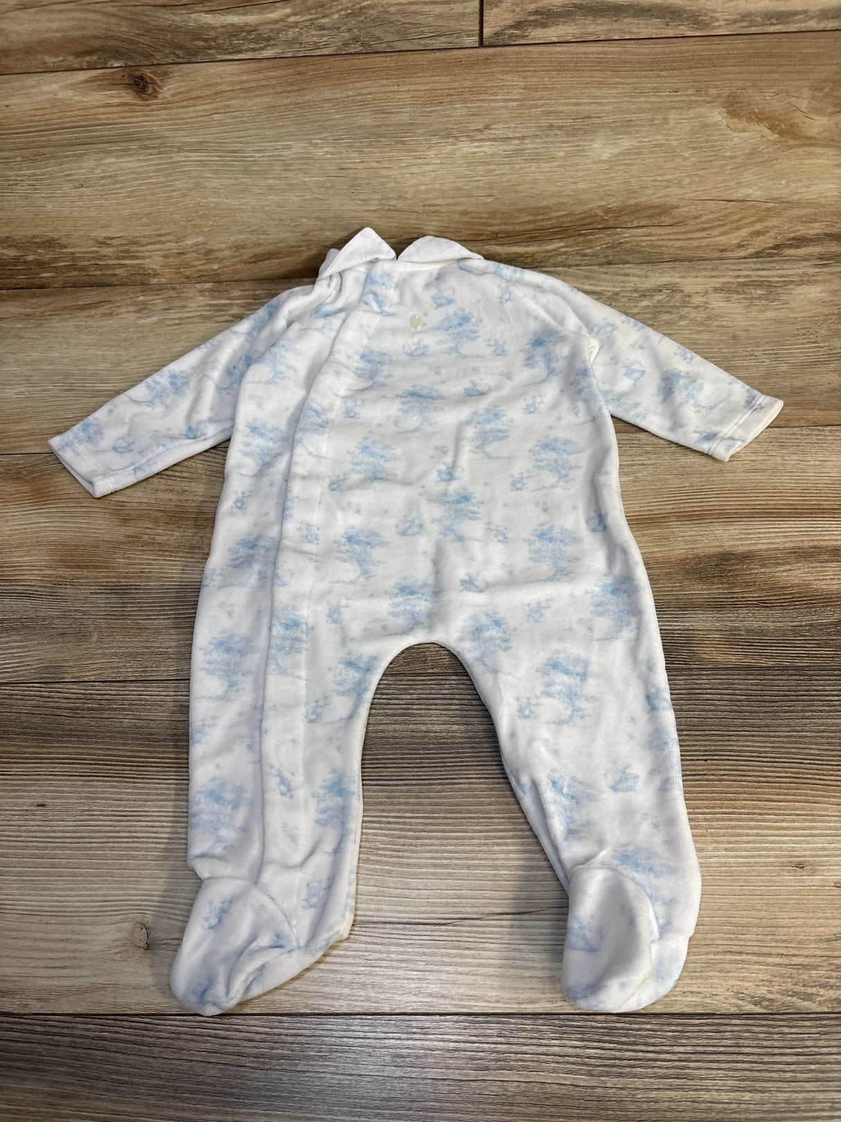 White and blue baby footed sleeper with long sleeves on a wooden floor
