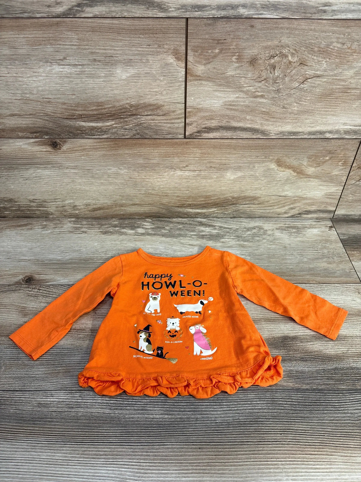 Front view of orange Carters Happy Howl O Ween shirt in size 12m showing long sleeves, ruffled hem, and animal graphics