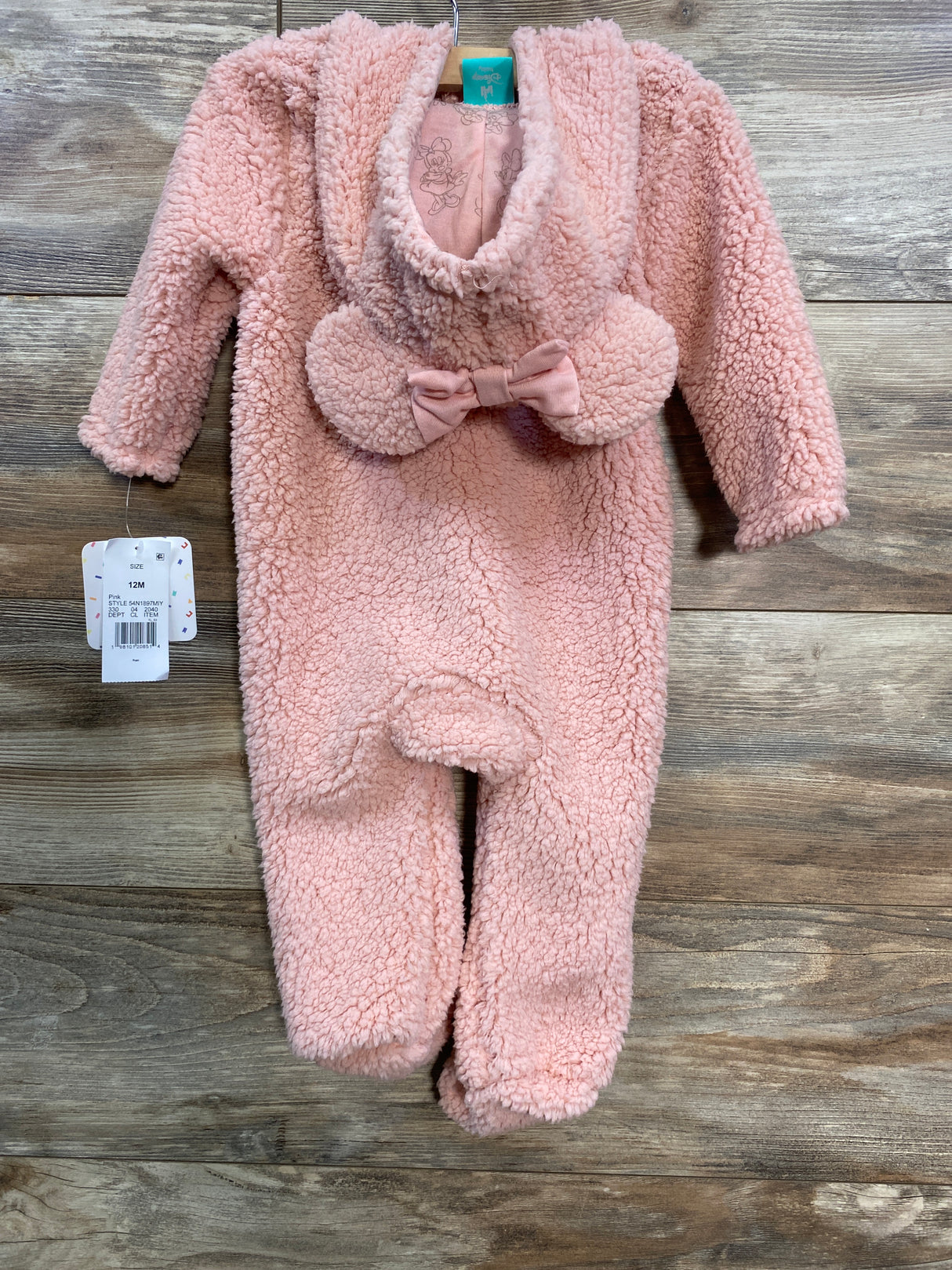 Pink fleece baby jumpsuit with bow detail and hood, size 12 months, hanging on wooden background