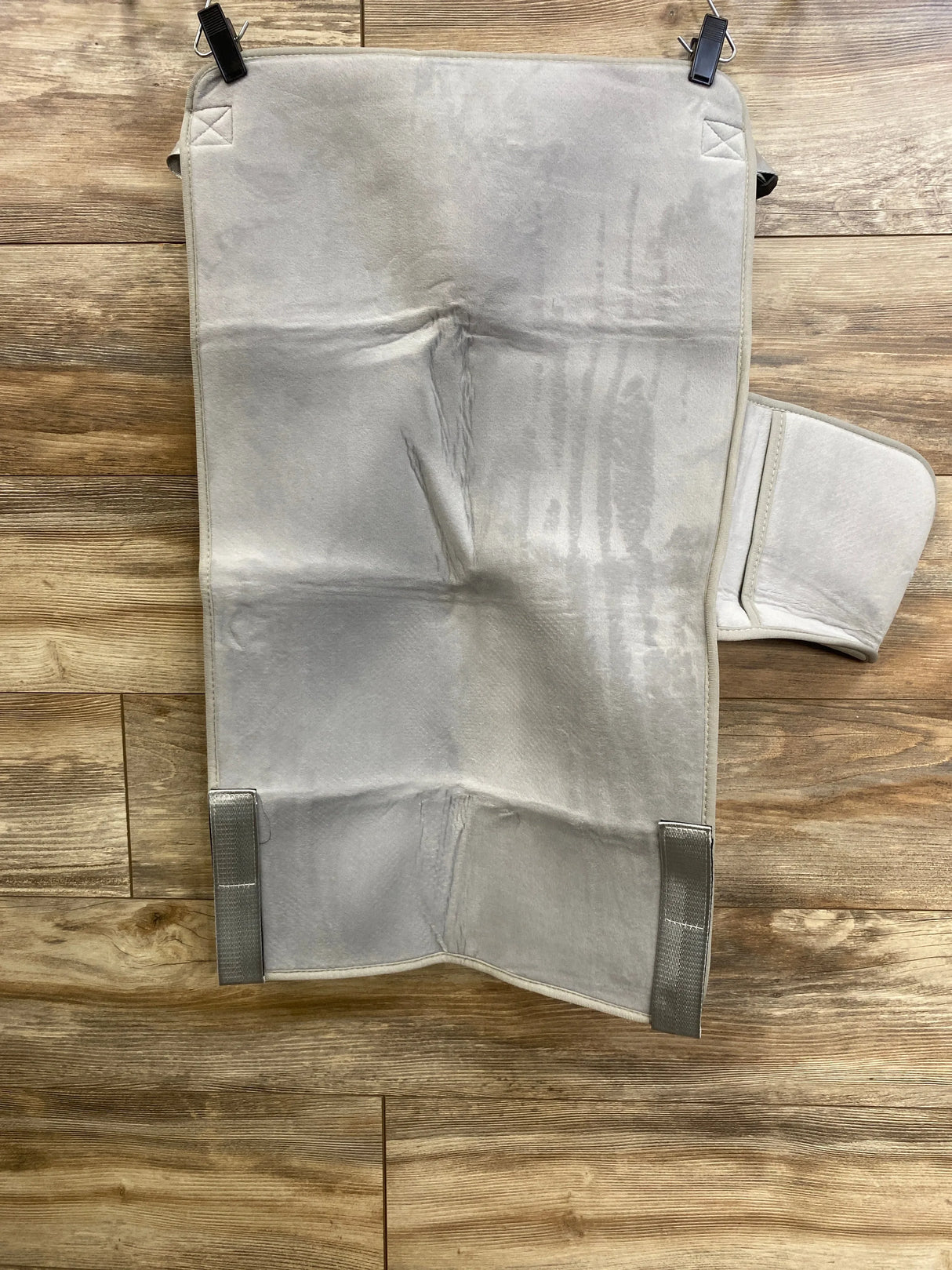 Top-down of Cozybonder toddler seat extender with padded grey surface, Velcro tabs and side flap on wood floor