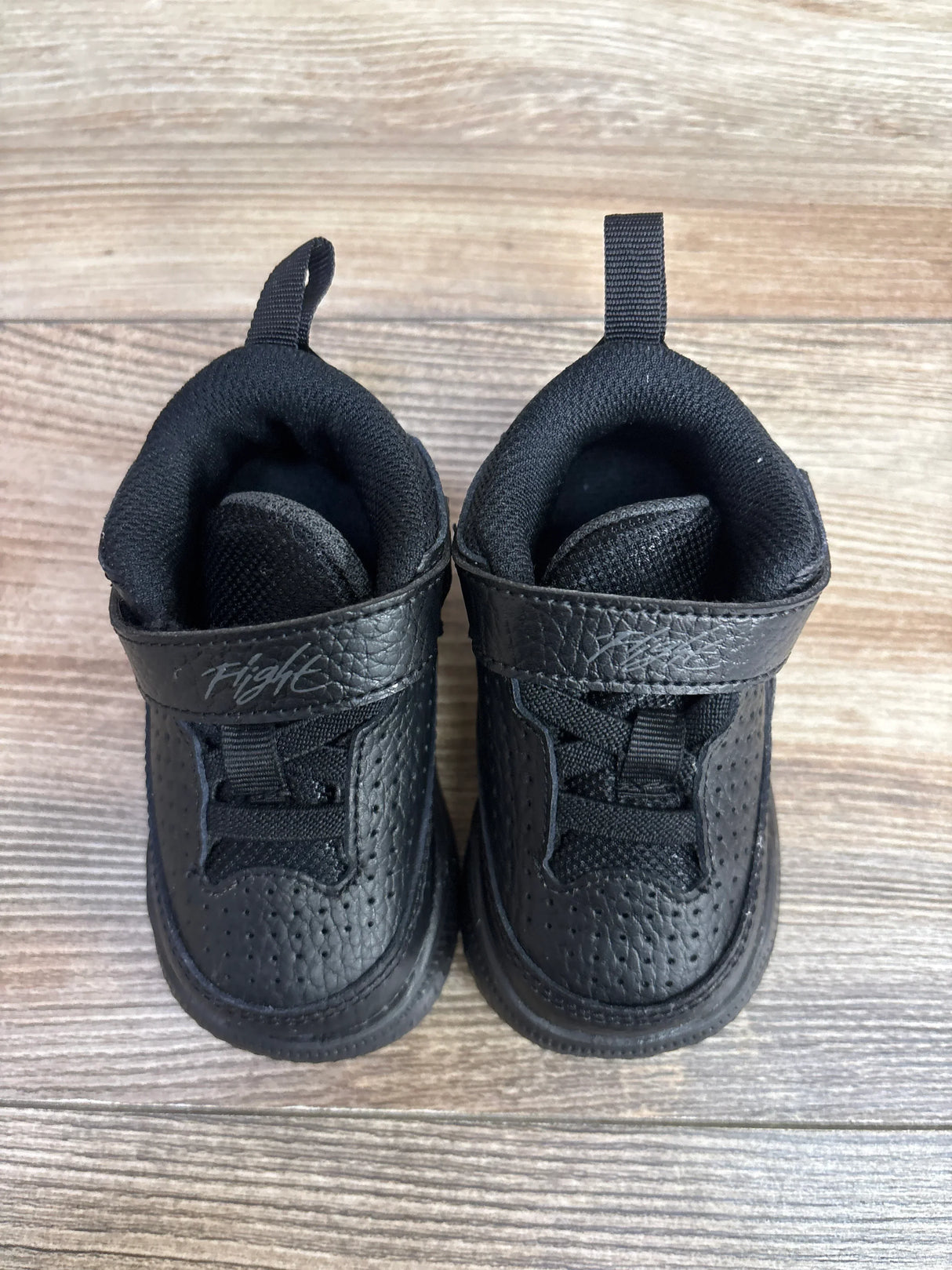 Top view of Air Jordan Max Aura 5 TD toddler sneakers in Black Anthracite showcasing Velcro strap labeled ‘Flight’ on wooden floor