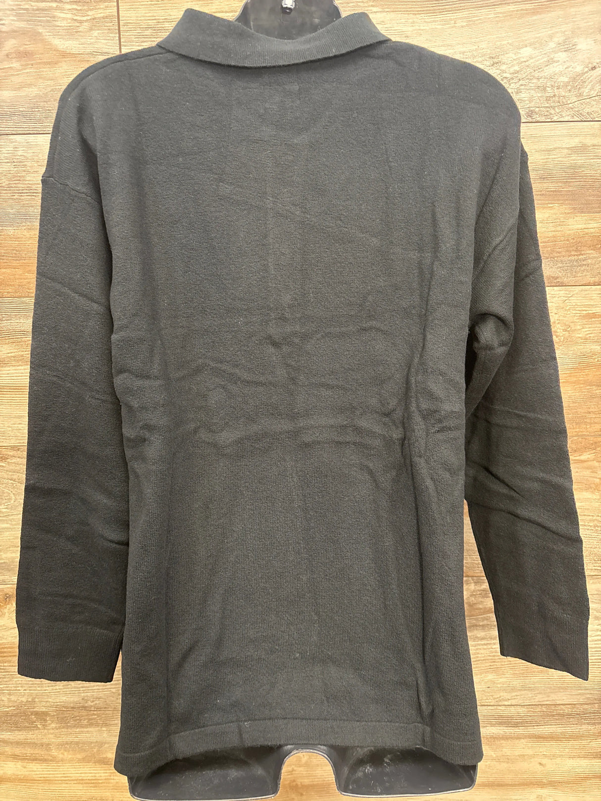 Black long-sleeve toddler shirt displayed on wooden background at children's resale store