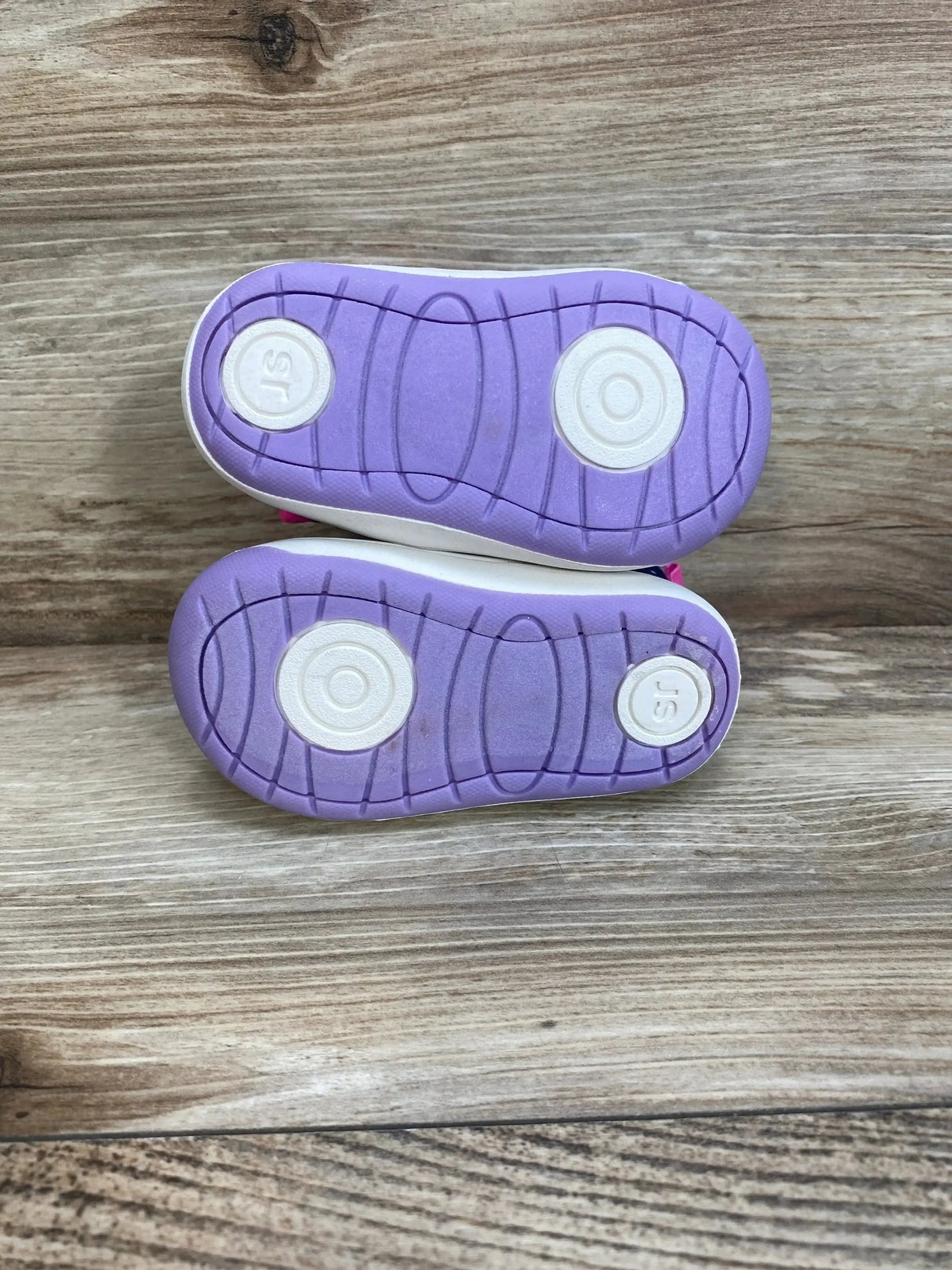 Top view of Surprize by Stride Rite Aster toddler winter boots showing purple rubber soles with circular tread and SR logo on wood background