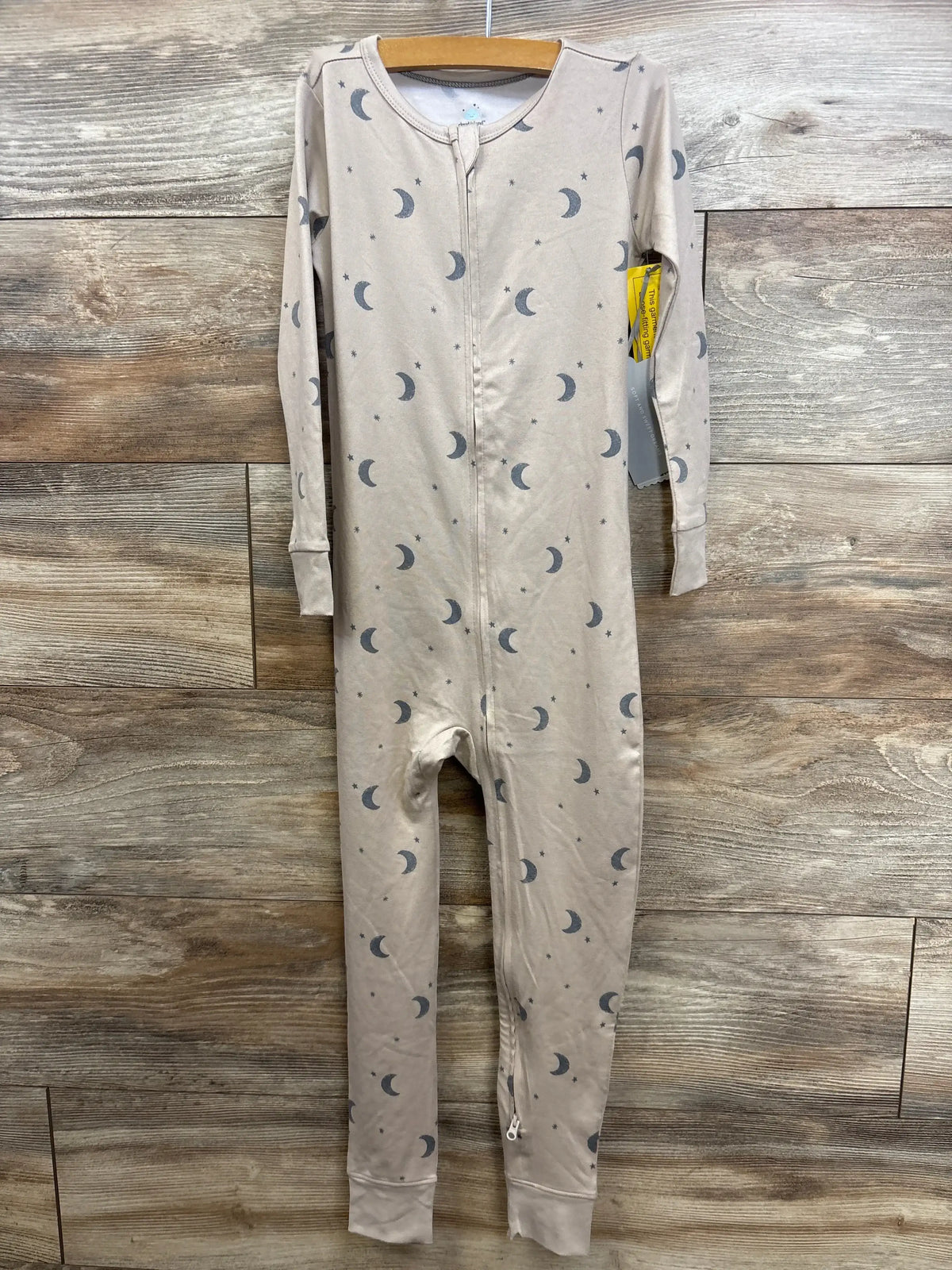 Front view of NEW Cloud Island tan moon print zip sleeper size 5T with hangtag on hanger over wood plank floor