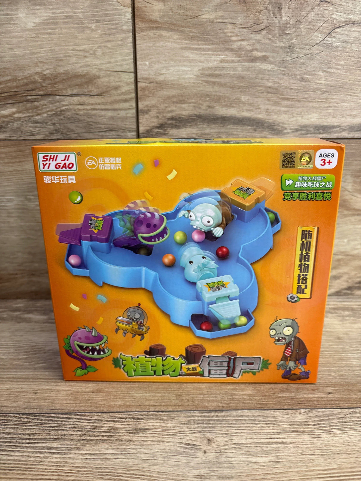 Front view of Plants vs Zombies Press and Play Game Board in orange retail box showcasing blue arena with zombie figures on wood floor