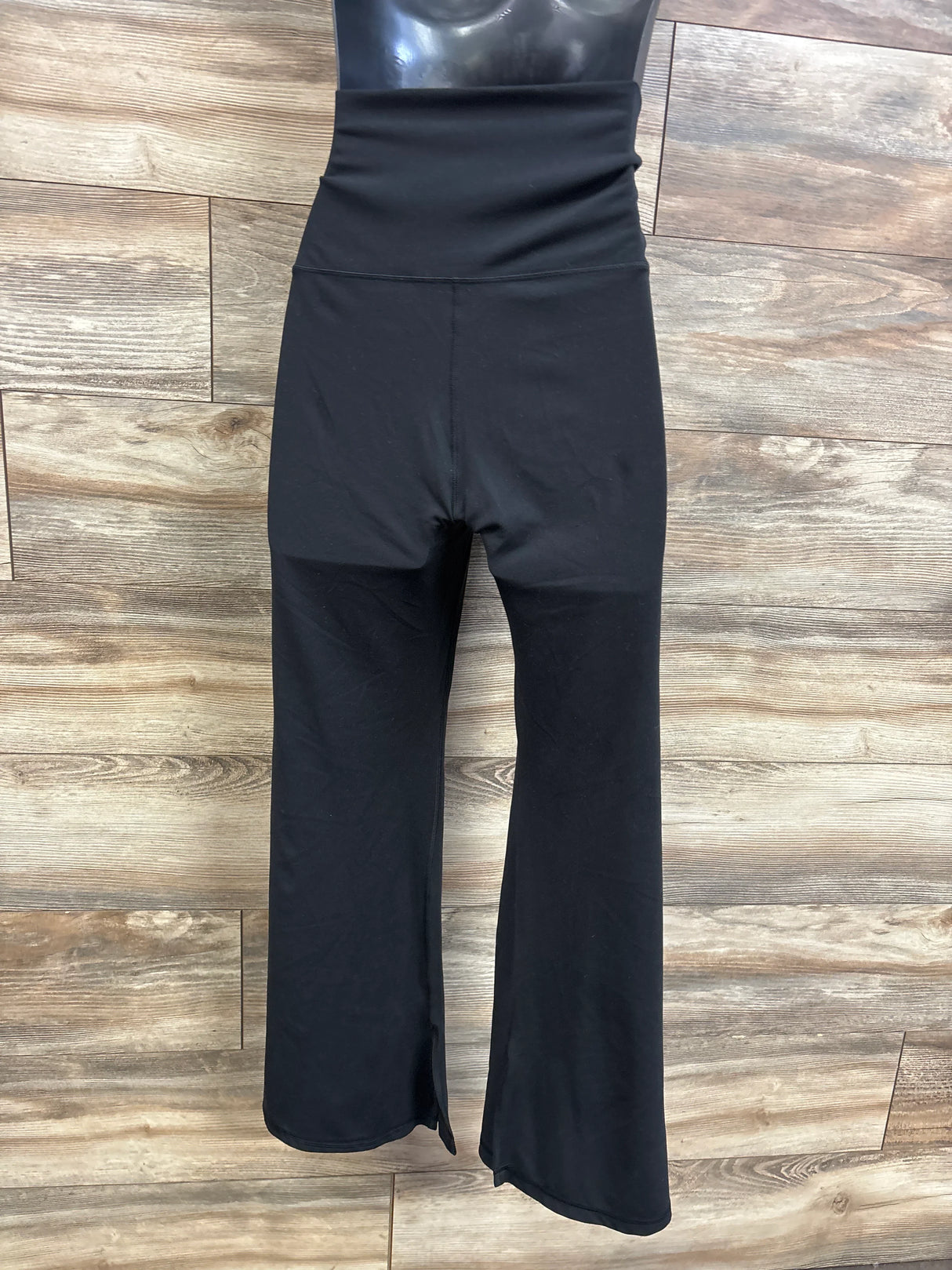 Front view of Isabel maternity leggings, black XL, showing high foldover waistband and slight flare against wood background