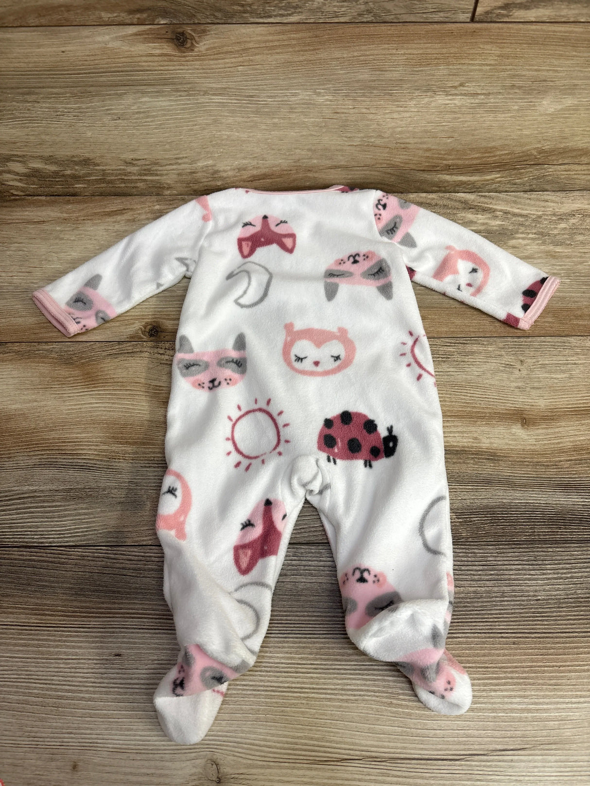 white baby fleece onesie with pink and gray animal and nature prints on wooden floor