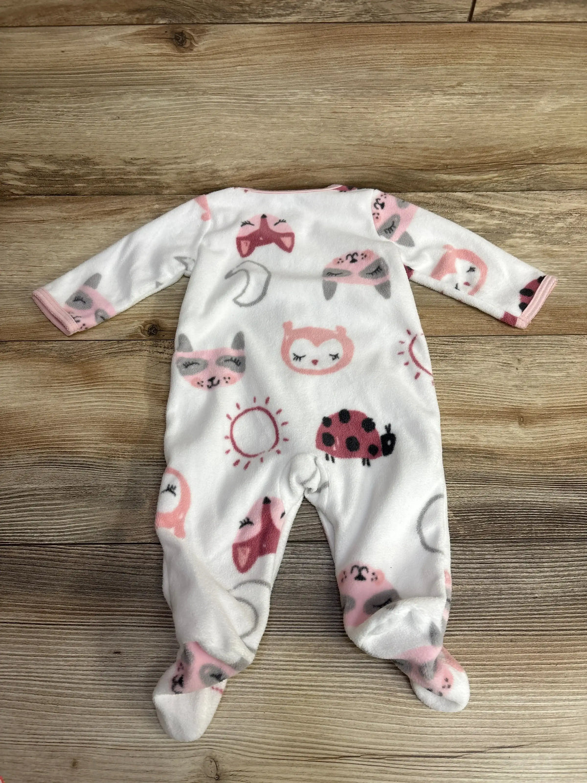 white baby fleece onesie with pink and gray animal and nature prints on wooden floor