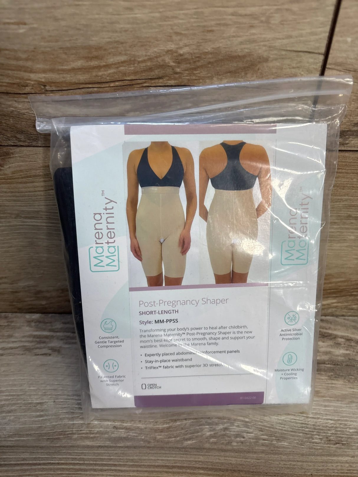 Front view of Marena Maternity post-pregnancy shaper in sealed package showcasing beige short-length compression shorts on wood plank floor