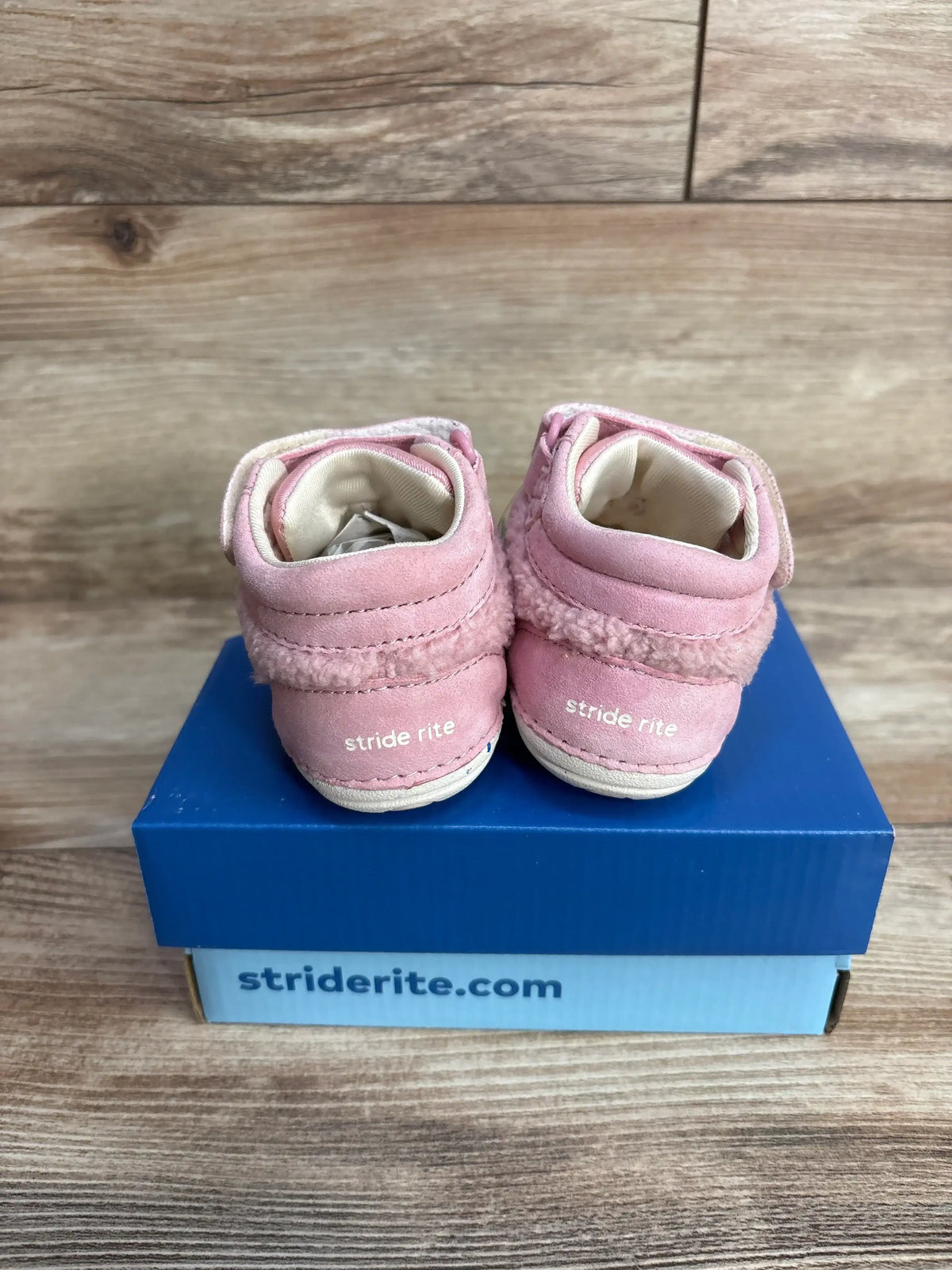Pair of pink Stride Rite baby shoes with fuzzy trim on blue Stride Rite box on wooden surface