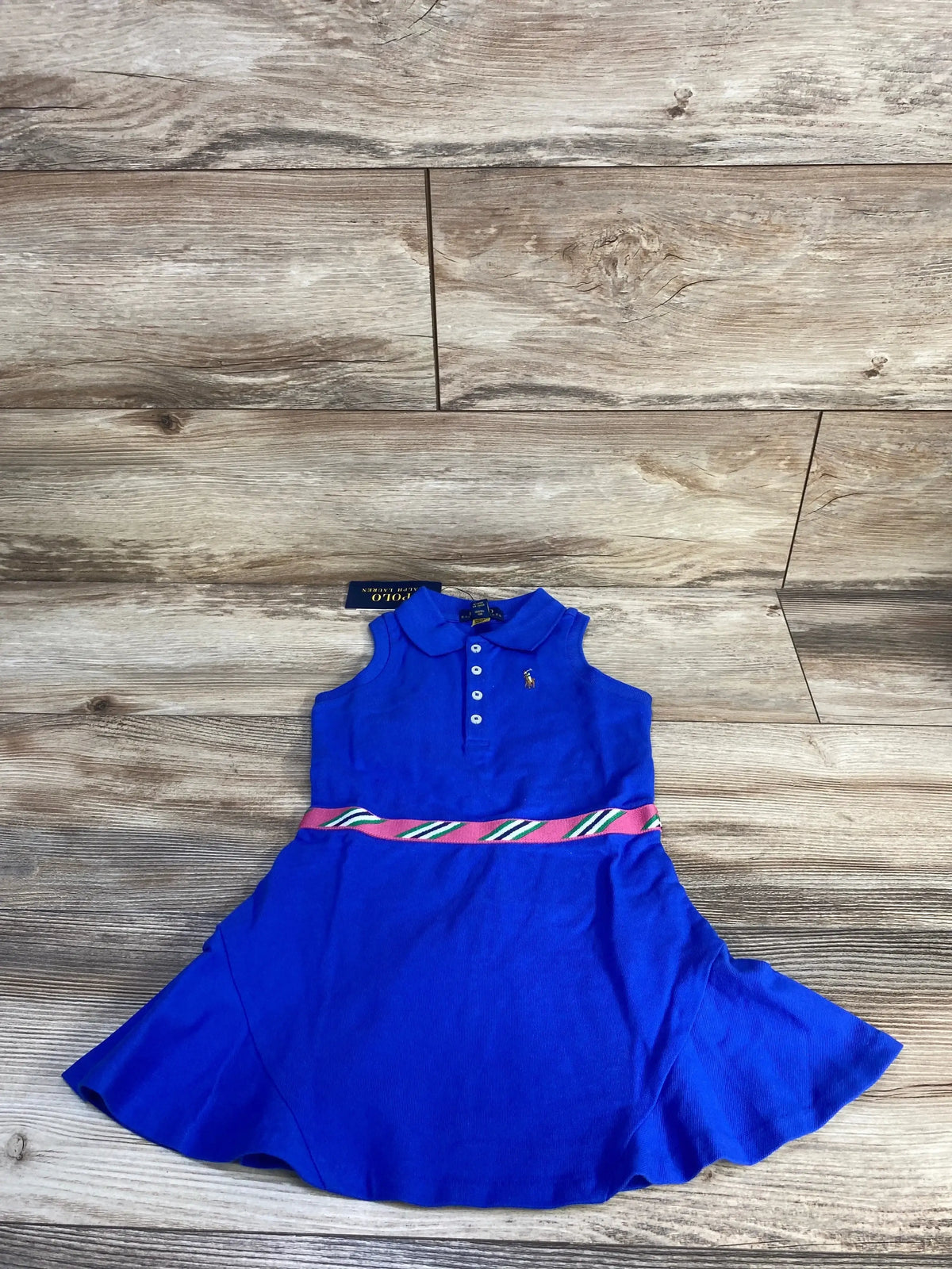 Flat-lay of Polo Ralph Lauren blue polo dress size 3T showing collared button bodice, striped ribbon waist on wood floor