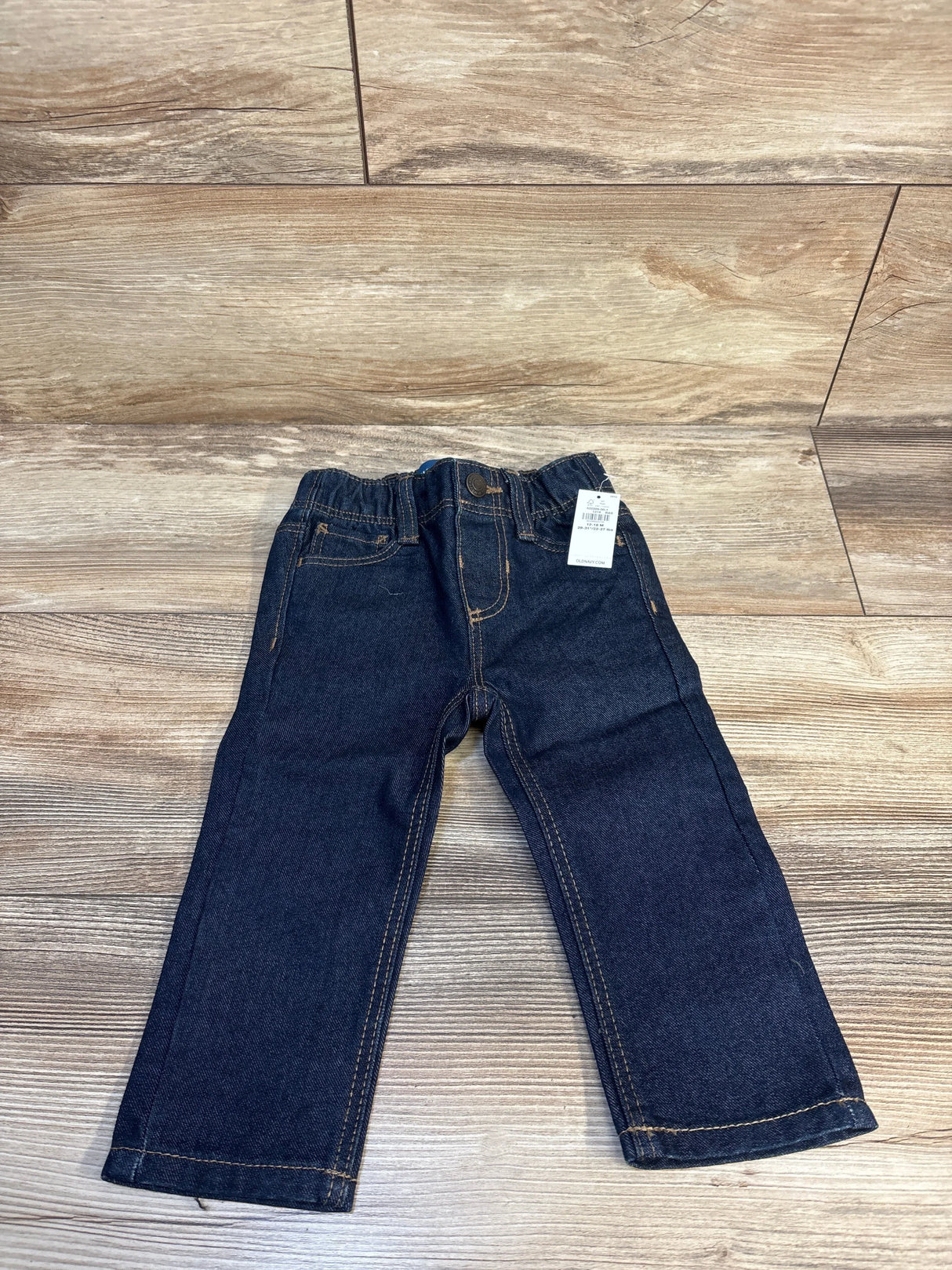 Front view of Old Navy straight jeans in dark blue, size 12 to 18 months, showcasing adjustable waist on wood-look flooring