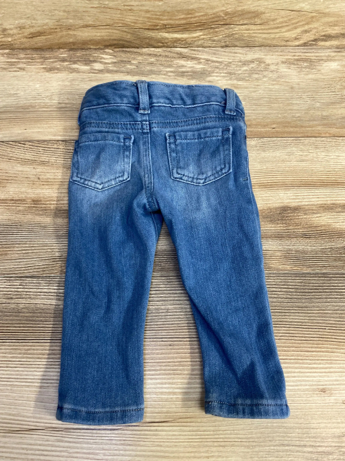 Back view of Cat and Jack blue 12m jeggings showcasing back patch pockets and adjustable elastic waistband on wood background