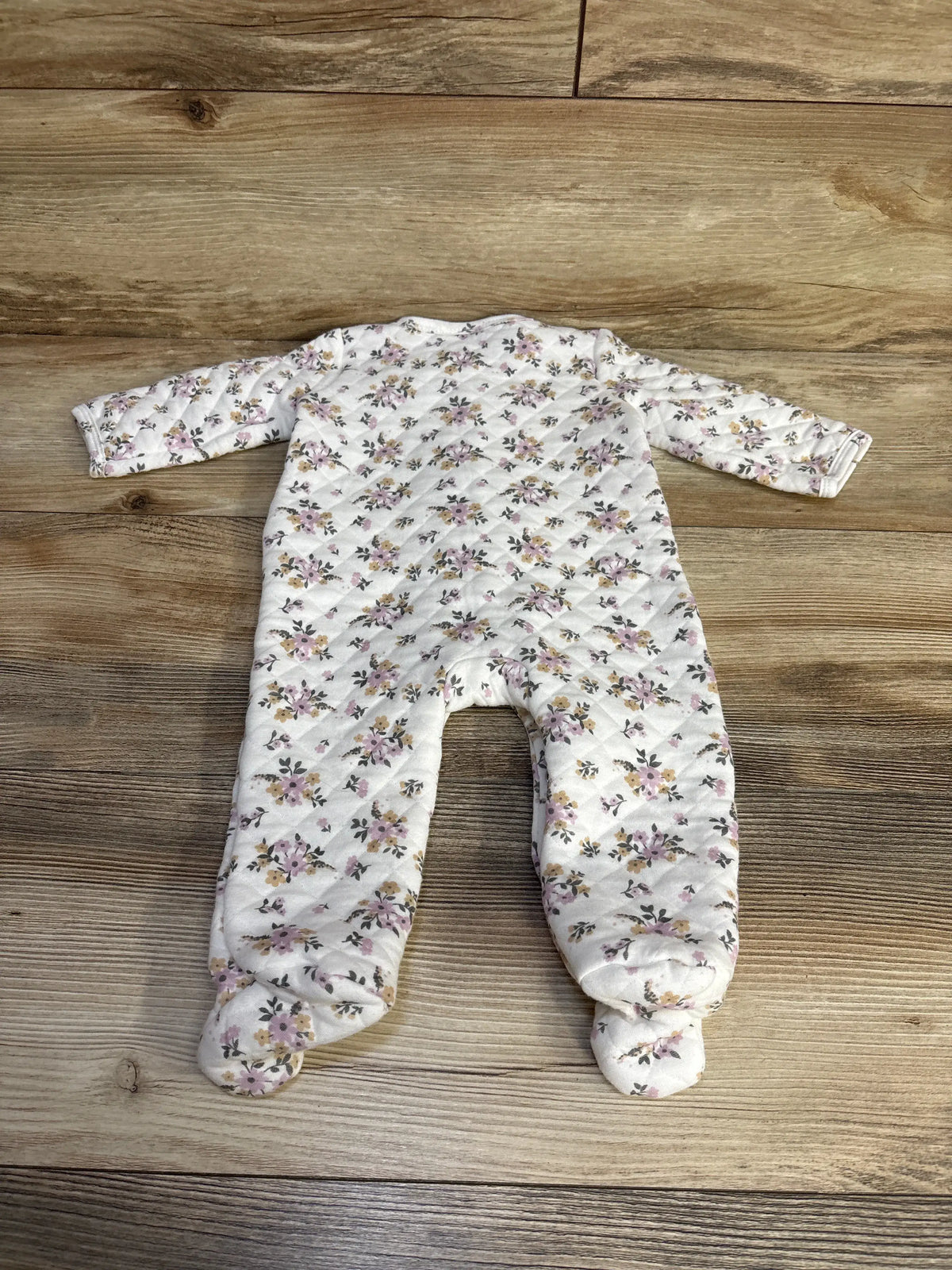 Top view of Nicole Miller floral quilted footed coverall in white showcasing enclosed feet on a wood floor