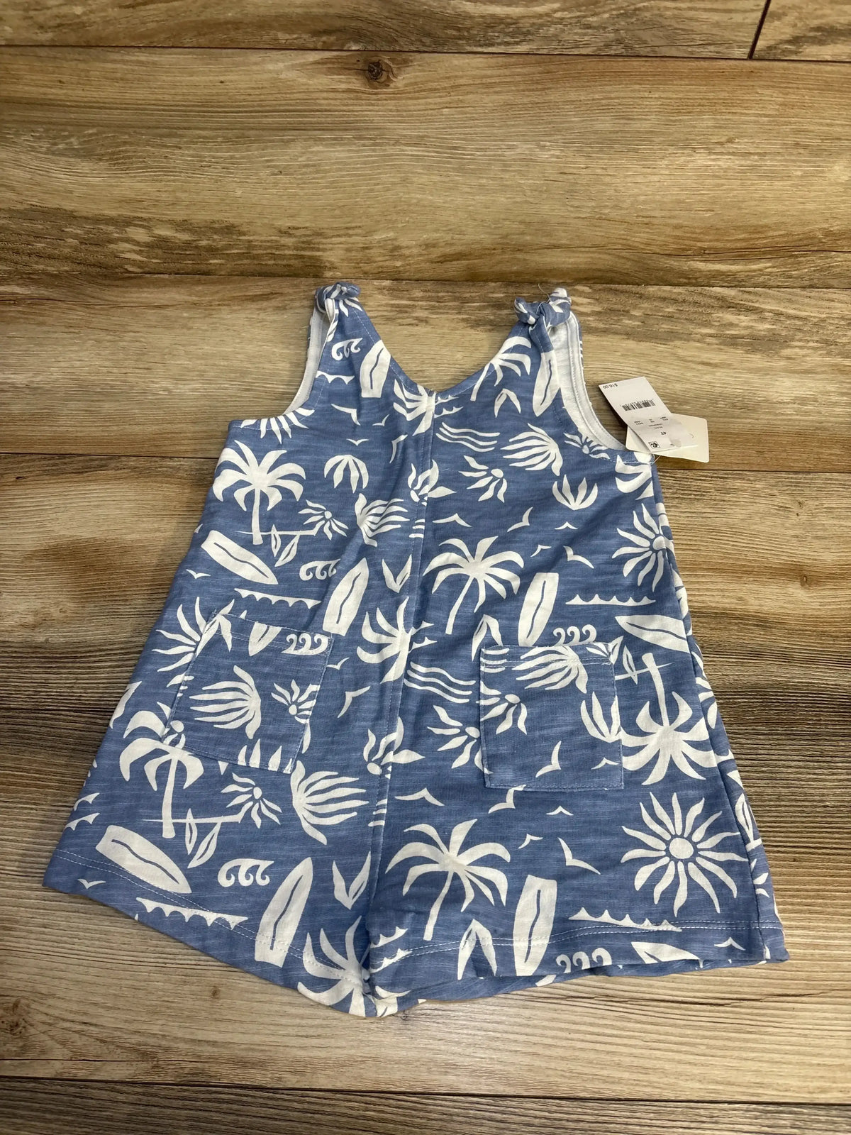 Blue toddler romper with white tropical palm and surfboard print on wooden background