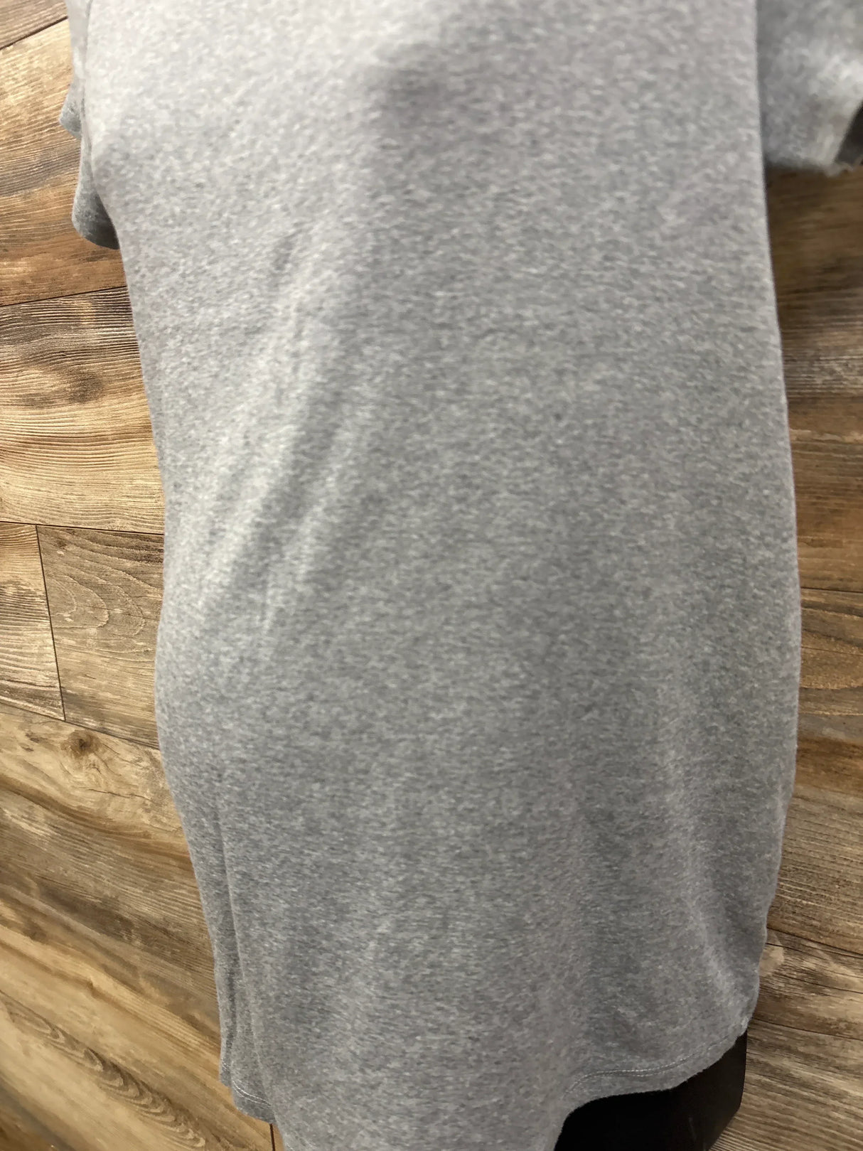 Back view of Isabel maternity shirt in heather grey, size Large, showing relaxed fit and curved hem against wood plank background