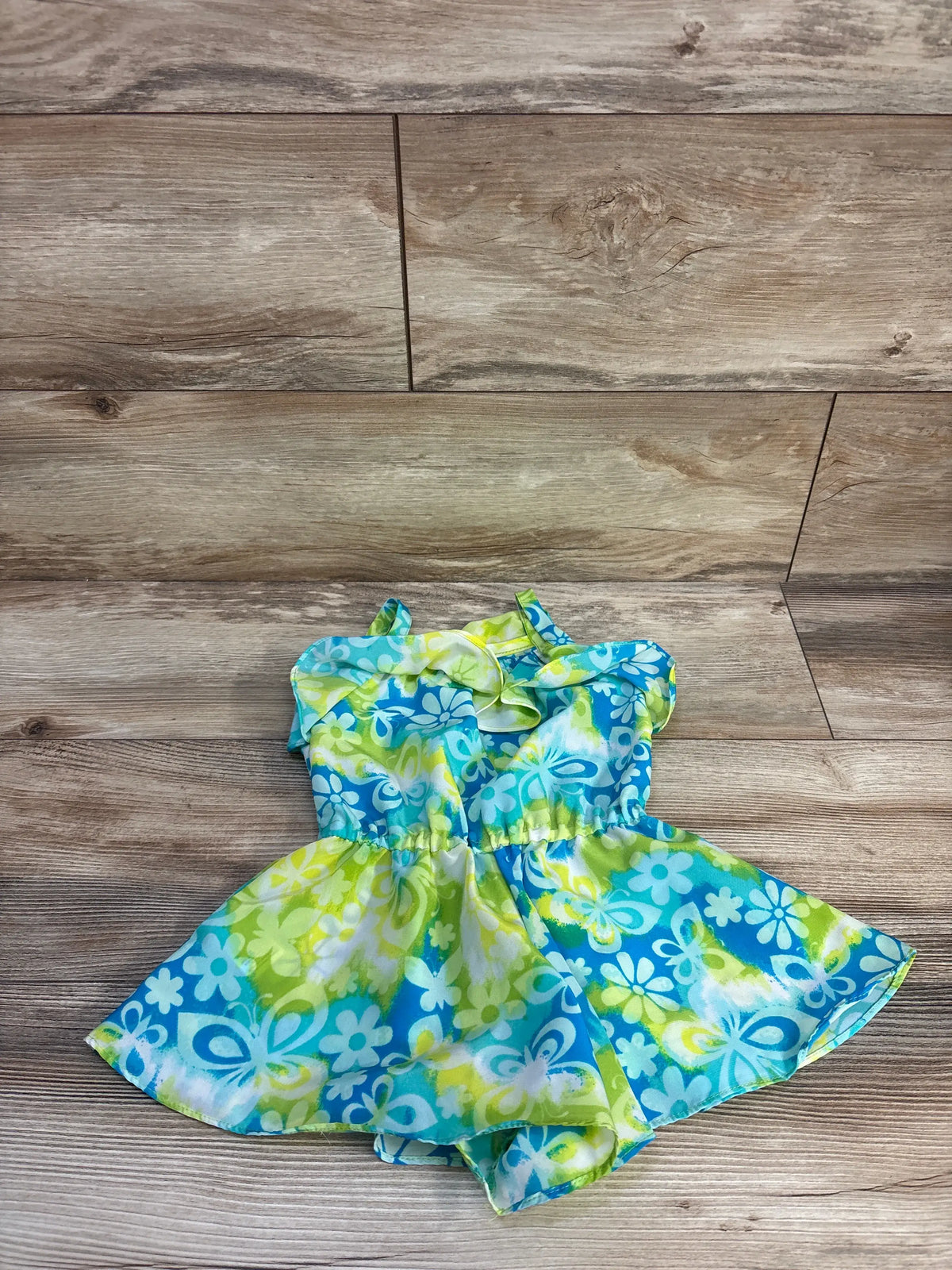 Front view of Youngland teal swim cover-up romper showcasing floral pattern and ruffled straps on a wood-look floor
