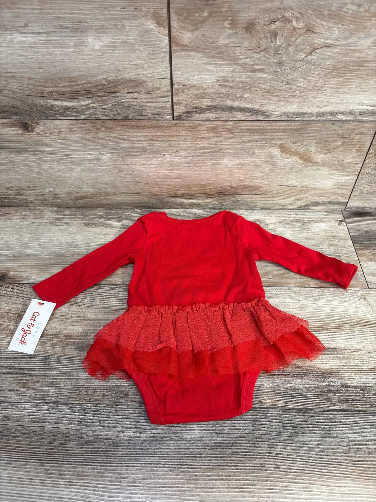 Red baby girl long sleeve romper with tutu skirt on wood background
