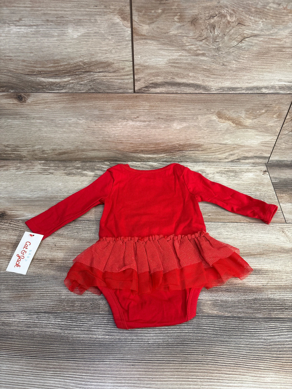 Red baby girl long sleeve romper with tutu skirt on wood background