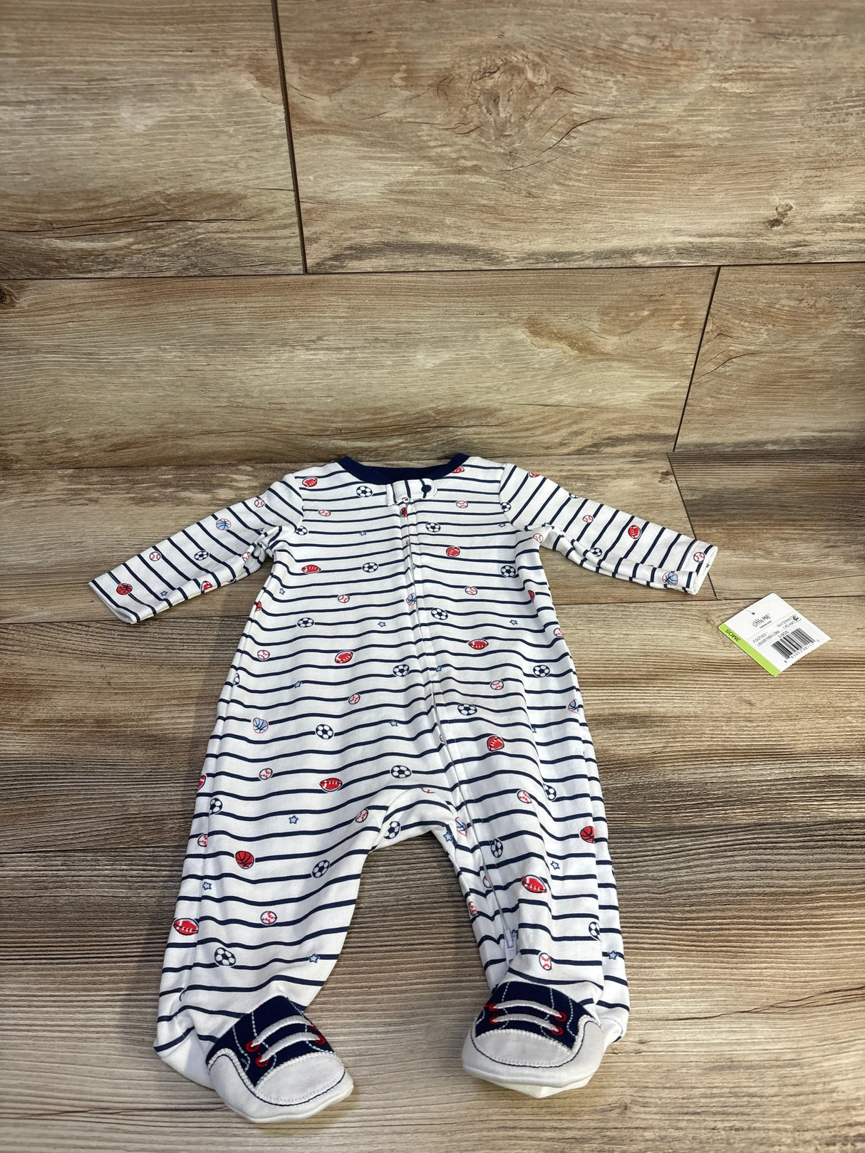 Front view of white navy striped footed baby sleeper with red and navy sports ball print, front zipper and sewn sneaker feet