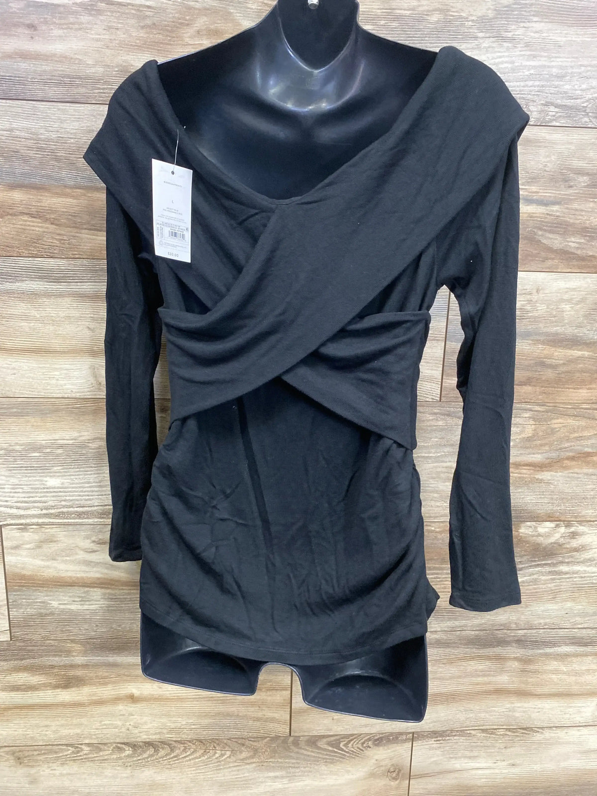 Black long sleeve maternity top with draped neckline on mannequin, wood background