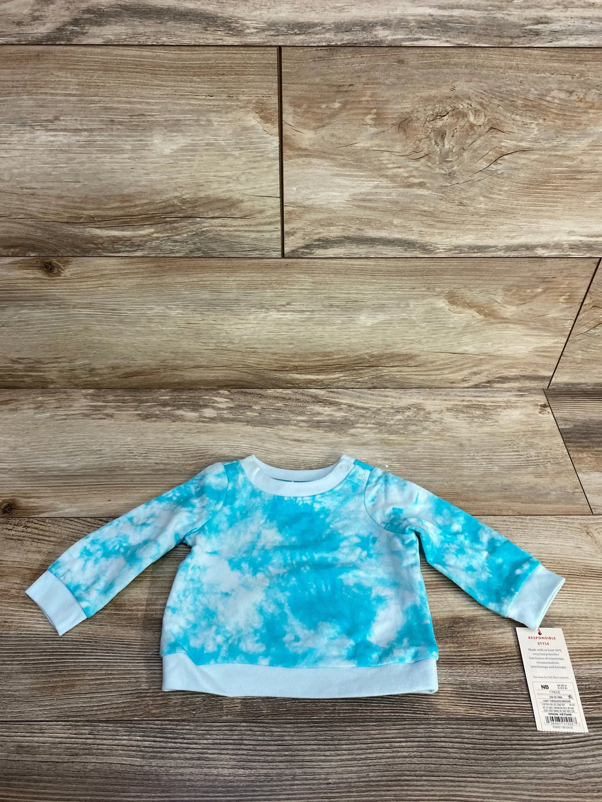 Blue and white tie dye newborn long sleeve shirt on wood background, baby clothing resale.