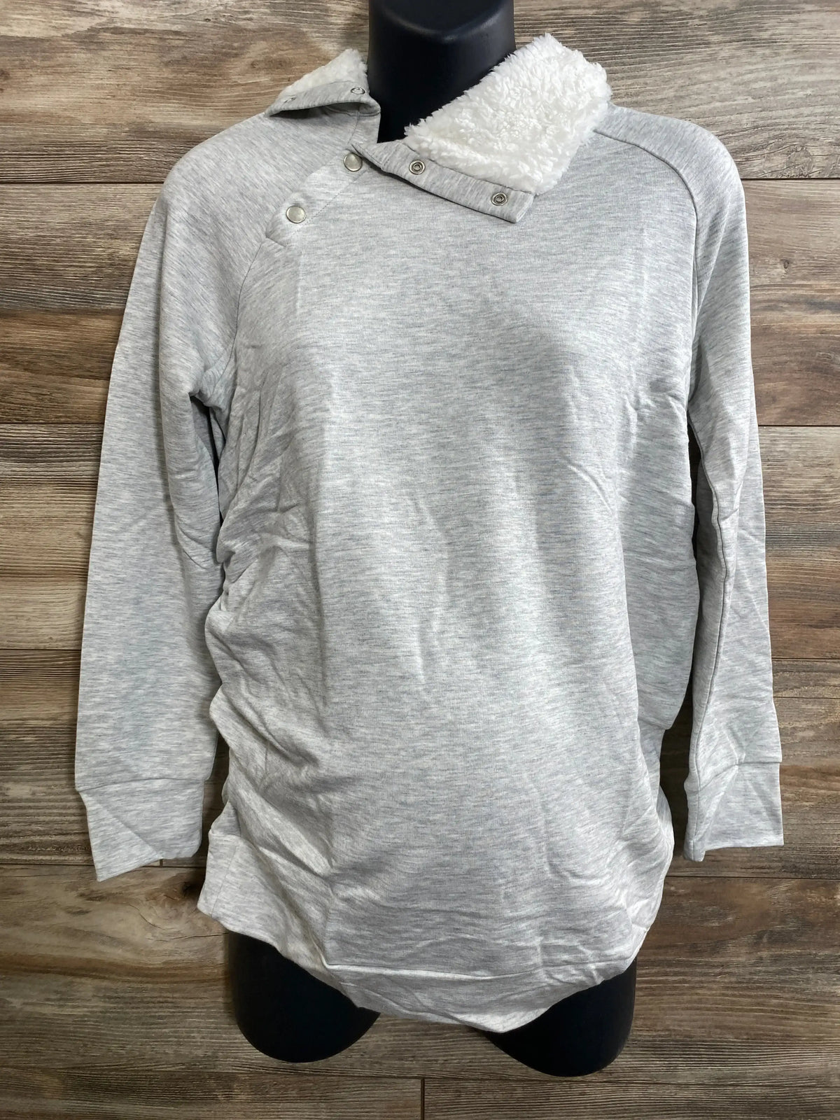 Front view of grey Isabel maternity sweatshirt on mannequin showcasing sherpa snap collar and side ruching with wood background