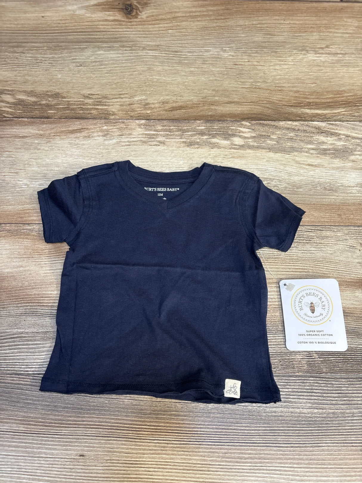 Front view of navy Burt’s Bees Baby raw hem shirt in 12 month size showcasing short sleeves and organic cotton on a wood floor
