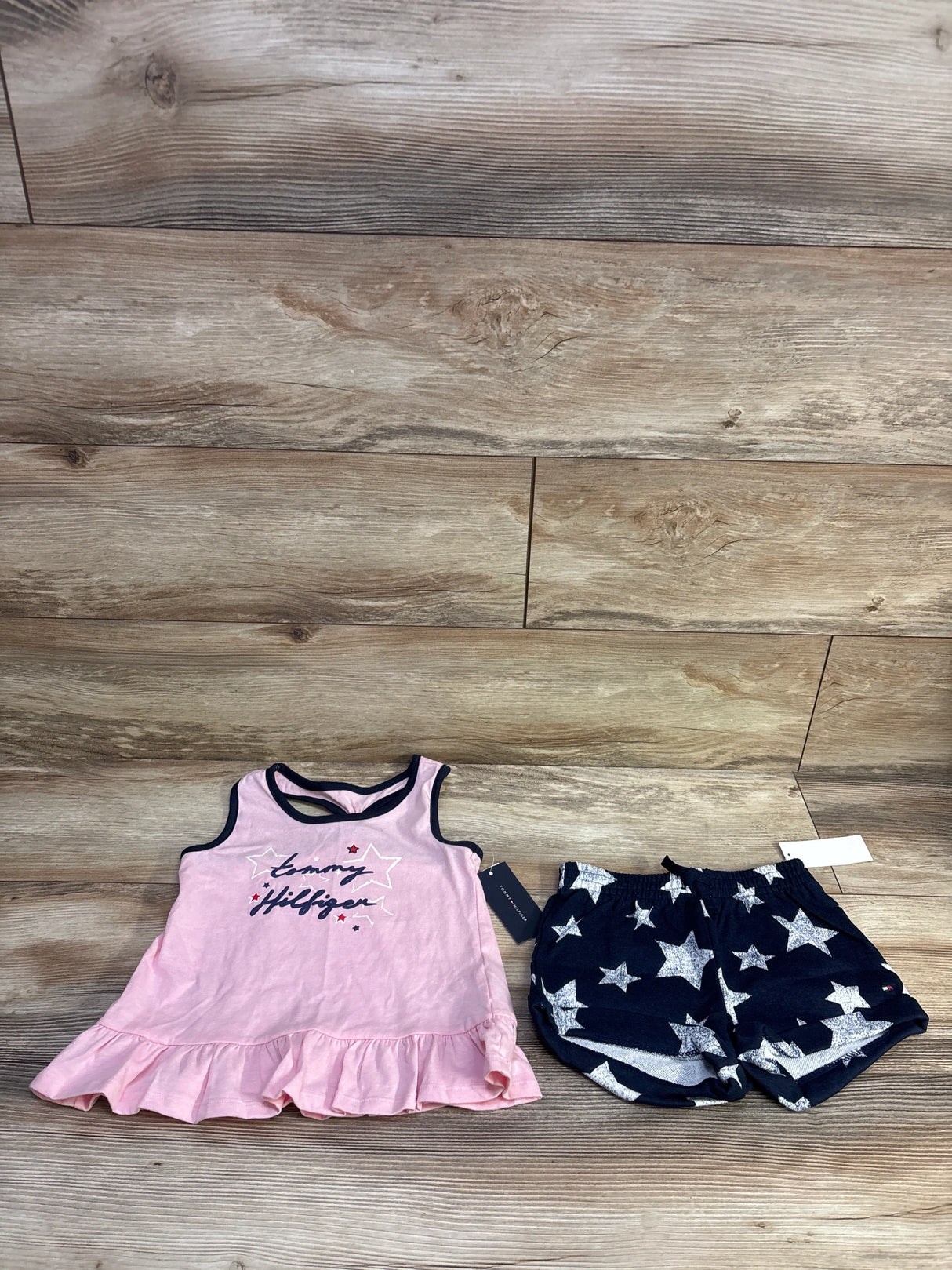 Flat lay of Tommy Bahama peplum tank and star-print shorts, pink ruffle top and navy shorts with white stars on wood