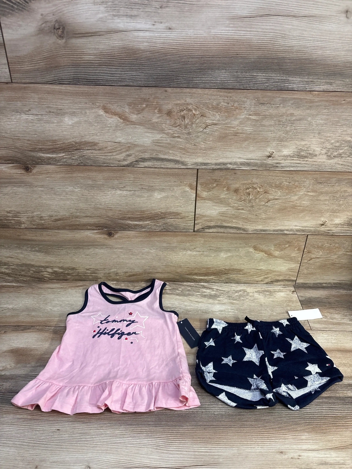 Flat lay of Tommy Bahama peplum tank and star-print shorts, pink ruffle top and navy shorts with white stars on wood