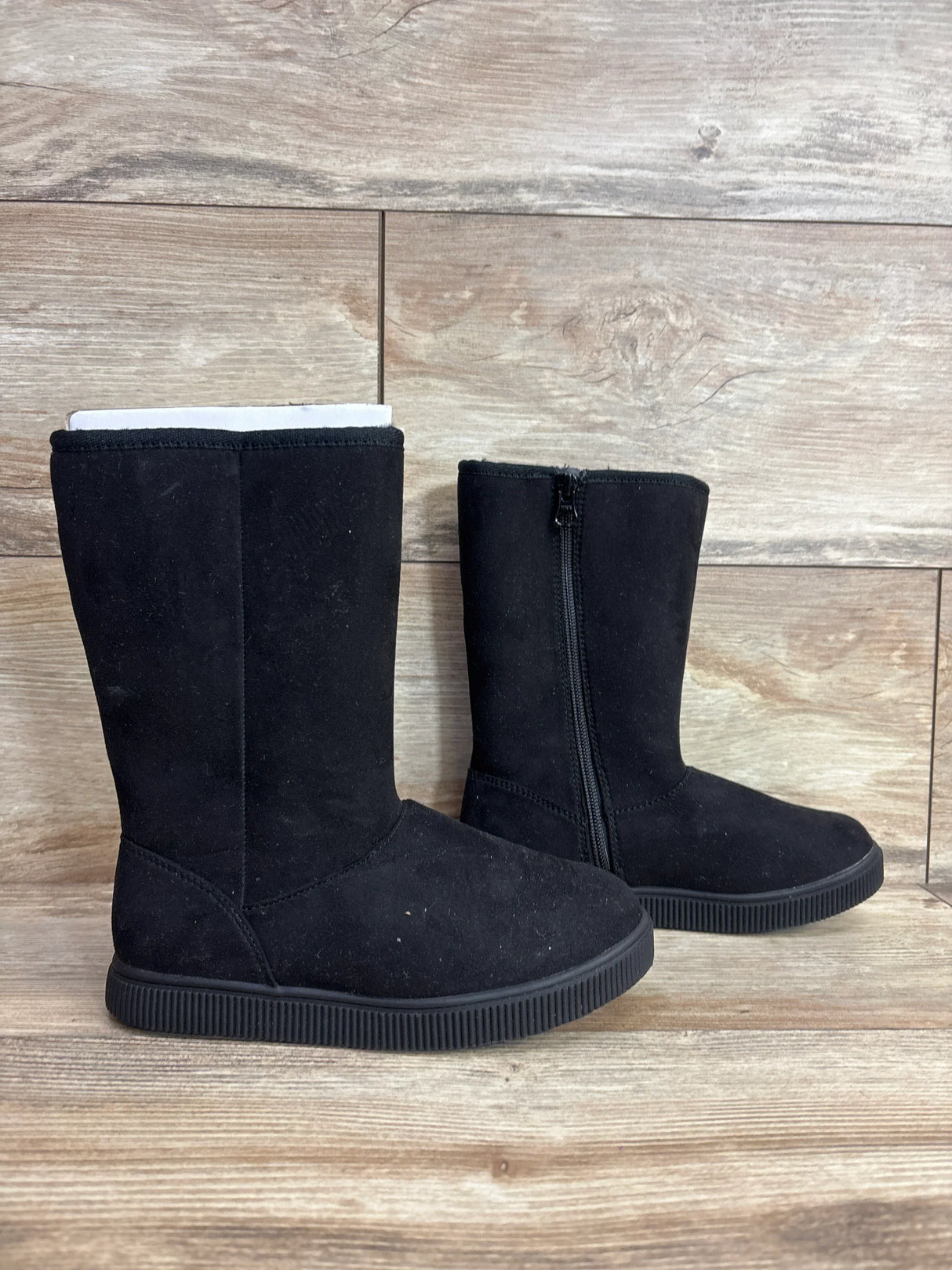 Black suede kids winter boots with side zipper on wood background