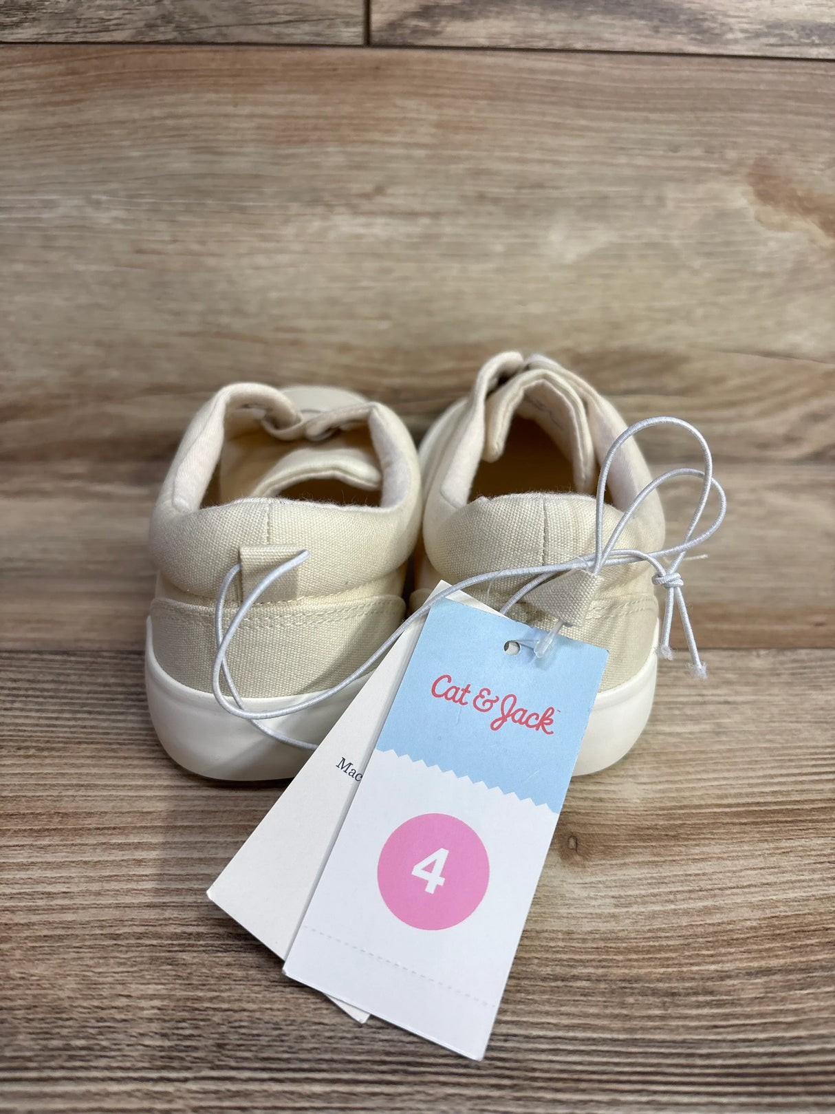 Beige toddler sneakers size 4 with tags on wooden background