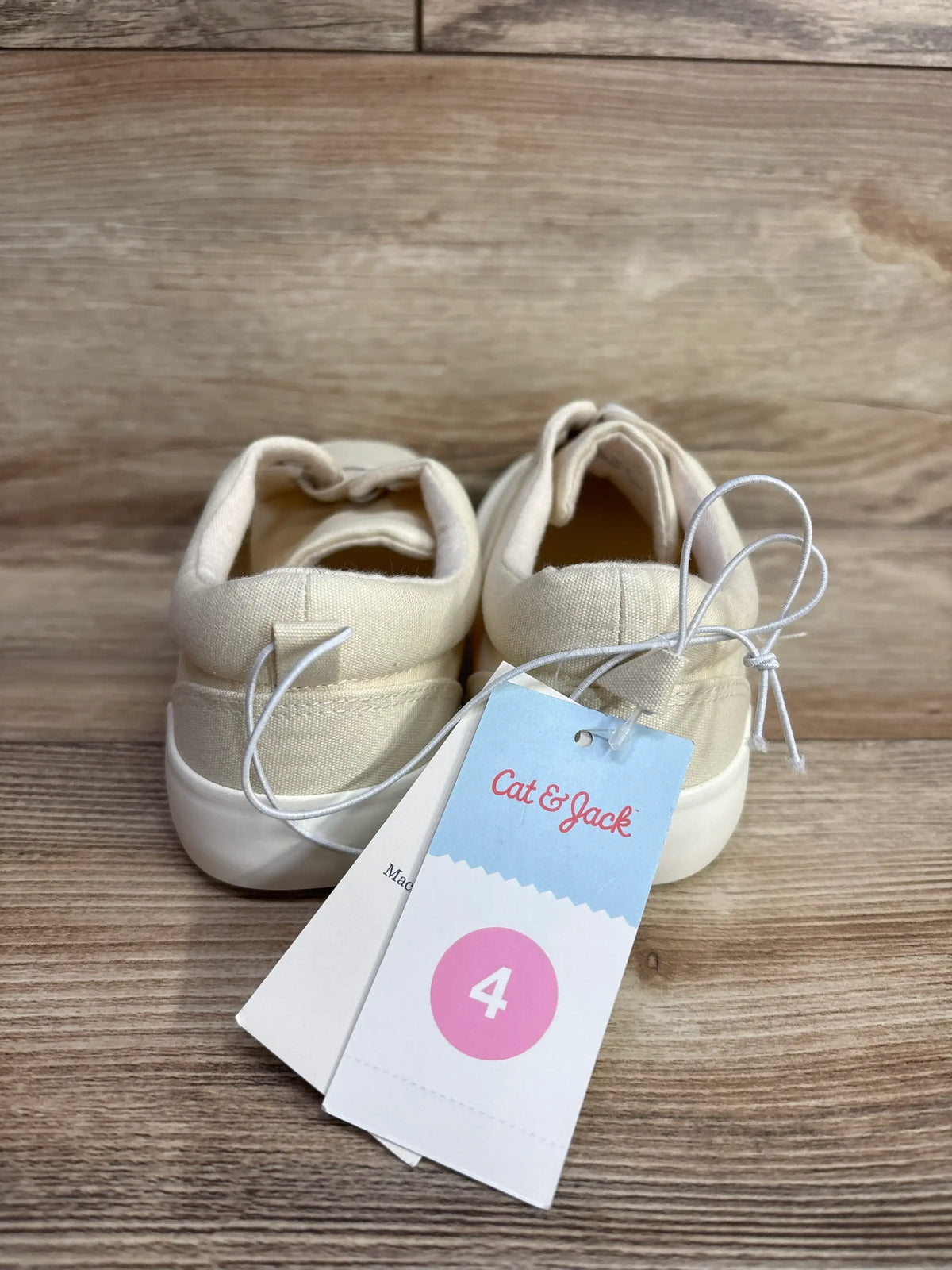 Beige toddler sneakers size 4 with tags on wooden background