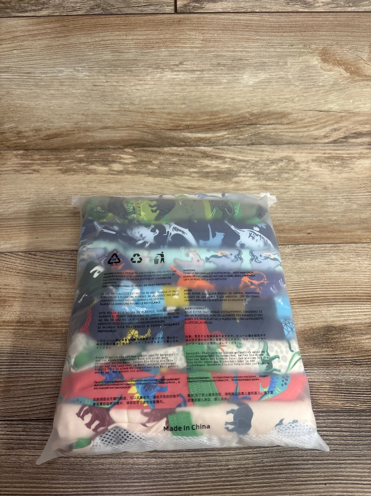 Top view of sealed bag containing EZ Moms 10-pack double absorption potty training underwear size 5T with colorful dinosaur print