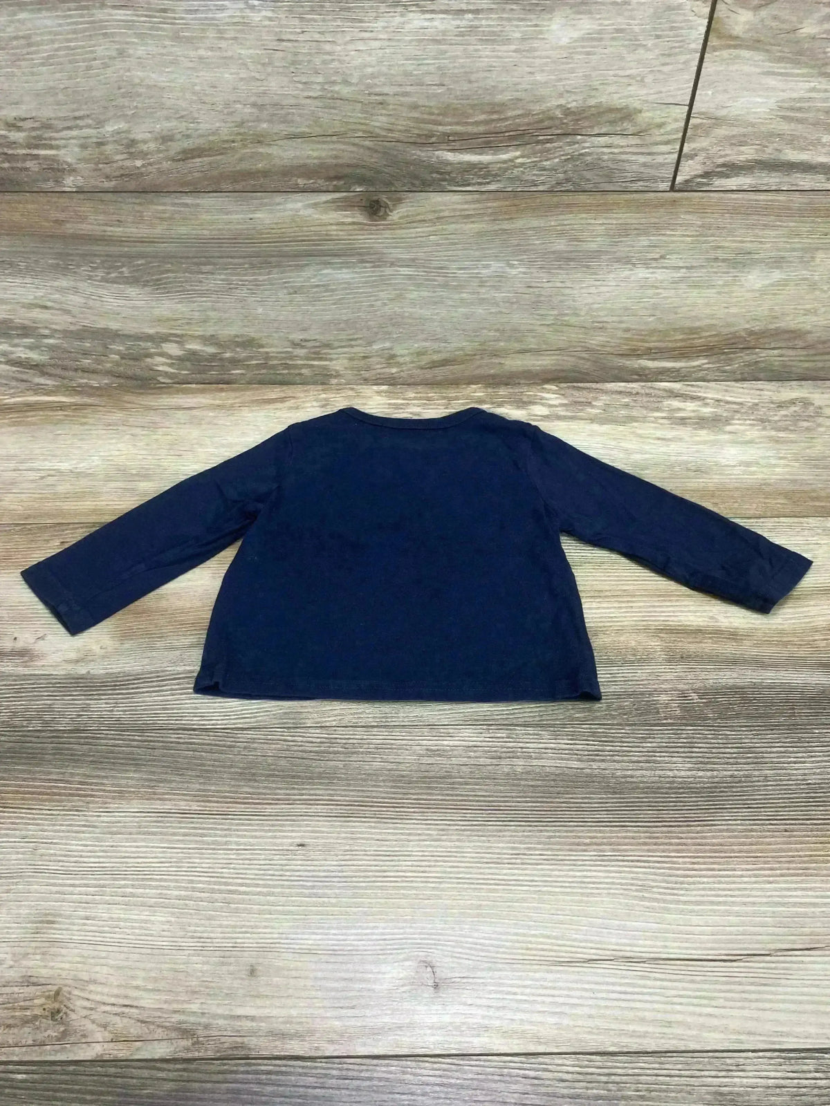 Back view of Children's Place navy long-sleeve baby shirt showcasing long sleeves and crew neckline laid flat on light wood background