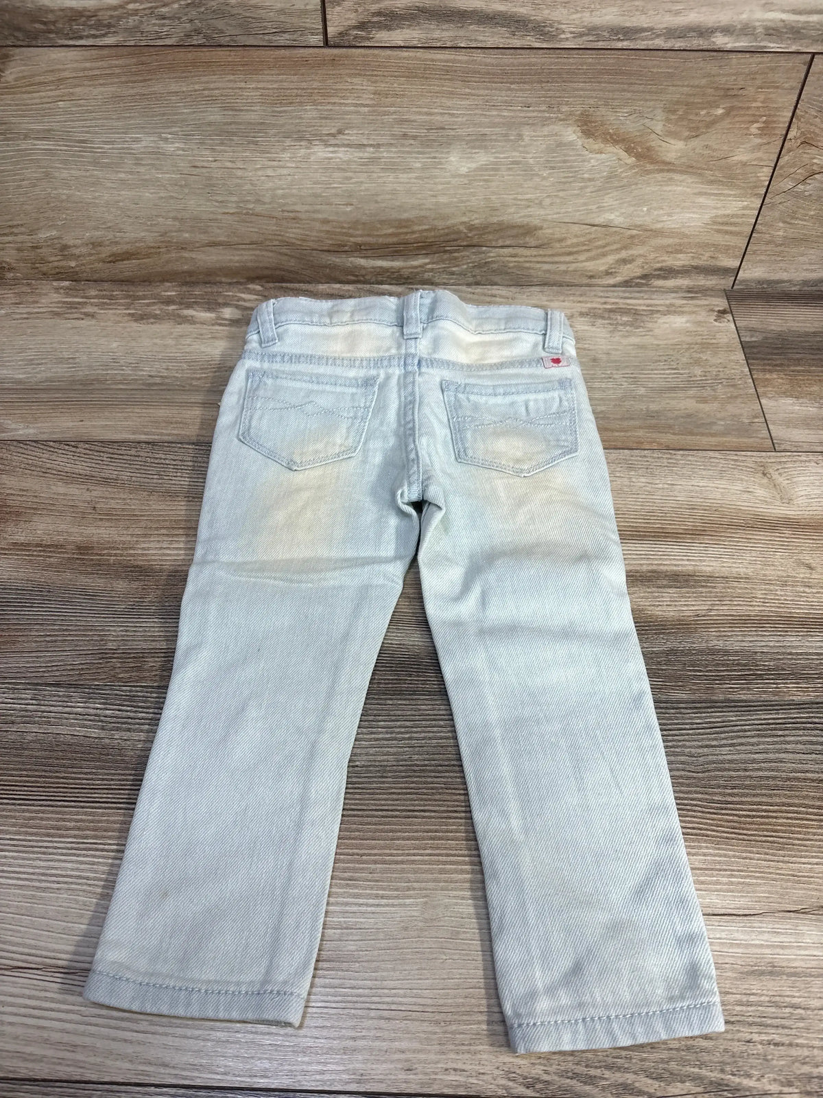 Back view of Lucky Brand Zoe toddler jeggings (2T) showcasing rear patch pockets and faded wash on wood floor background