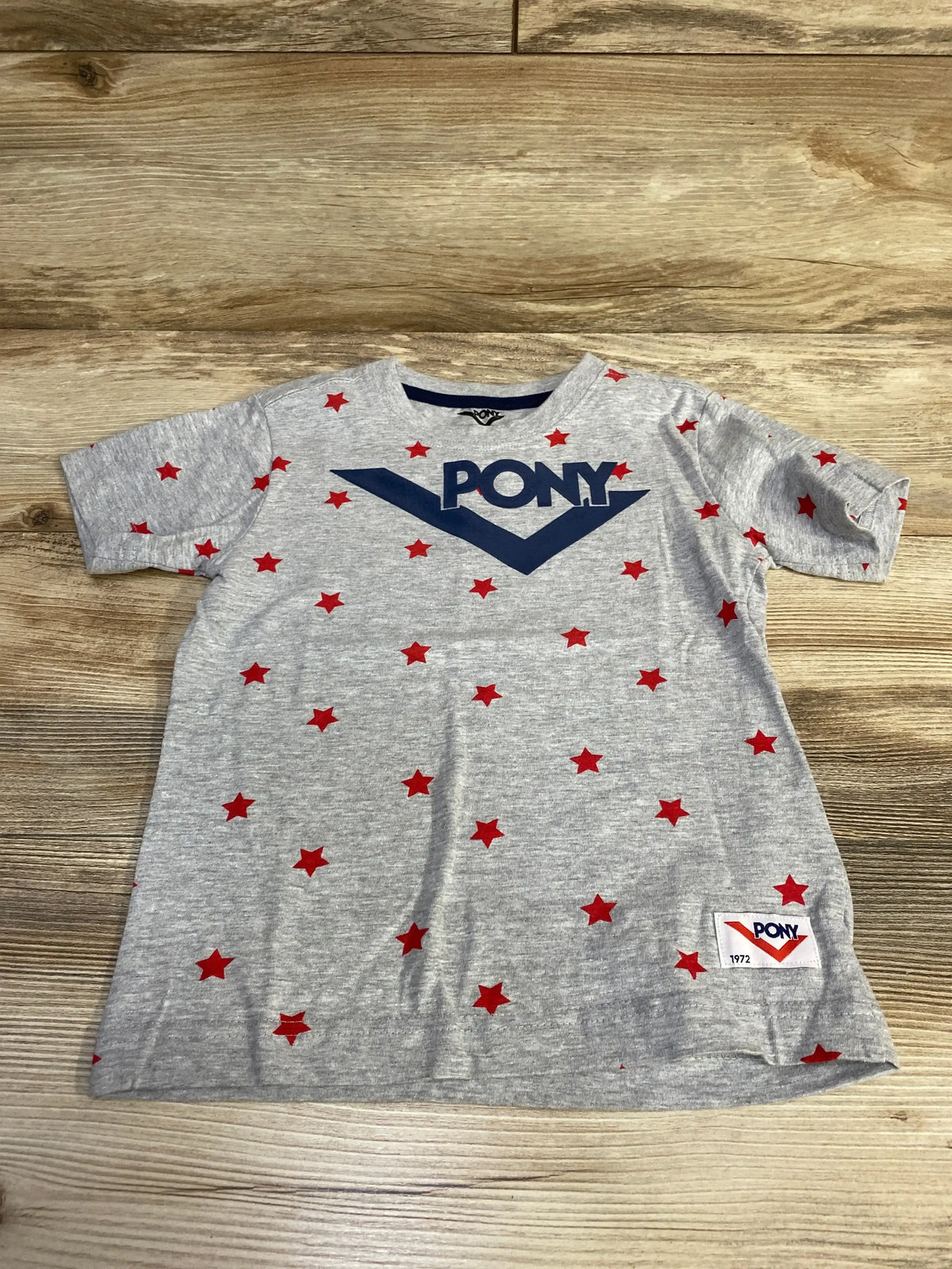 Flat lay of grey toddler short-sleeve Pony shirt (4T) showing navy PONY logo, red star print, crew neck, brand patch on wood floor